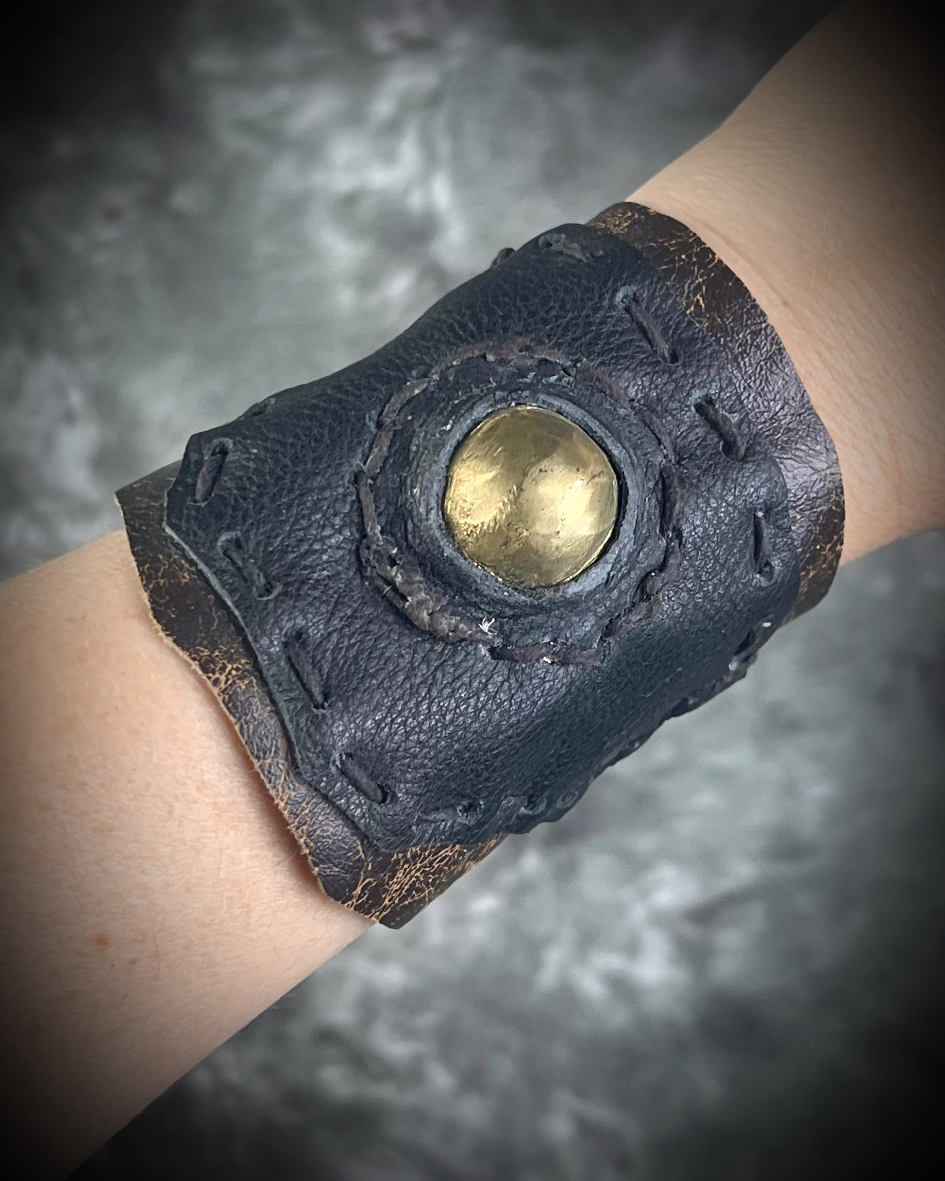 Handmade extra wide 3-inch leather cuff bracelet with layered black and brown leather, brass details, hand stitching, and adjustable leather tie closure by Anothai Hansen.