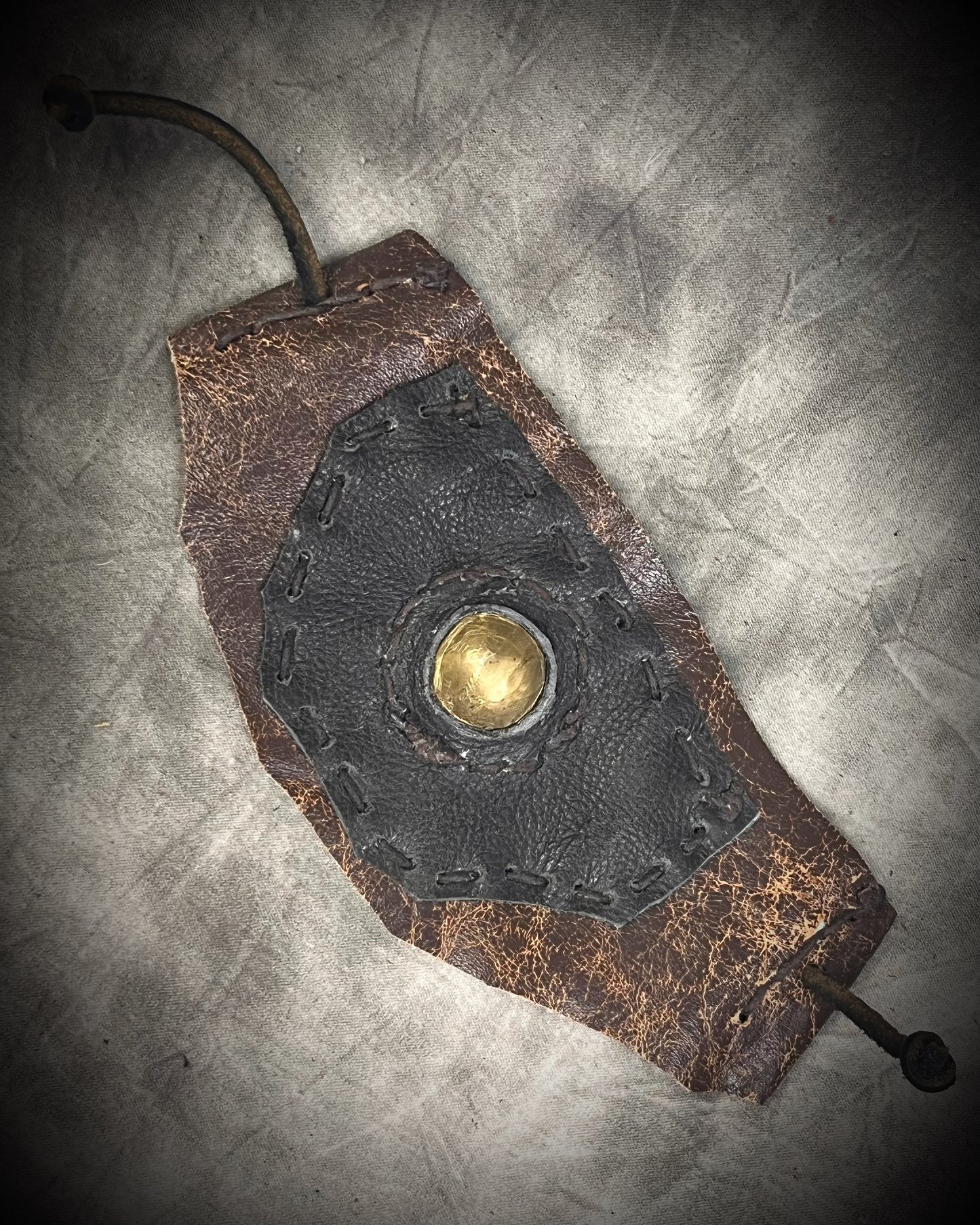 Handmade extra wide 3-inch leather cuff bracelet with layered black and brown leather, brass details, hand stitching, and adjustable leather tie closure by Anothai Hansen.