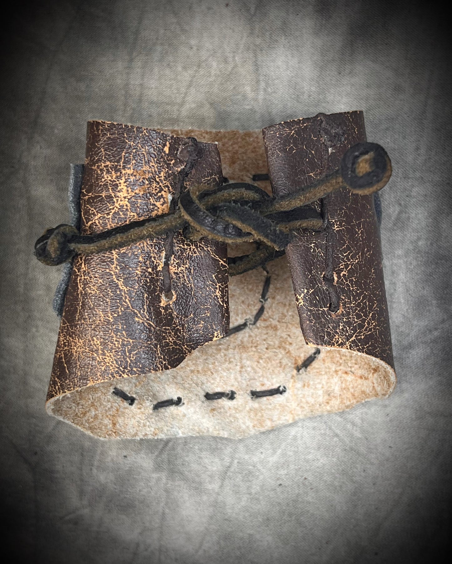 Handmade extra wide 3-inch leather cuff bracelet with layered black and brown leather, brass details, hand stitching, and adjustable leather tie closure by Anothai Hansen.