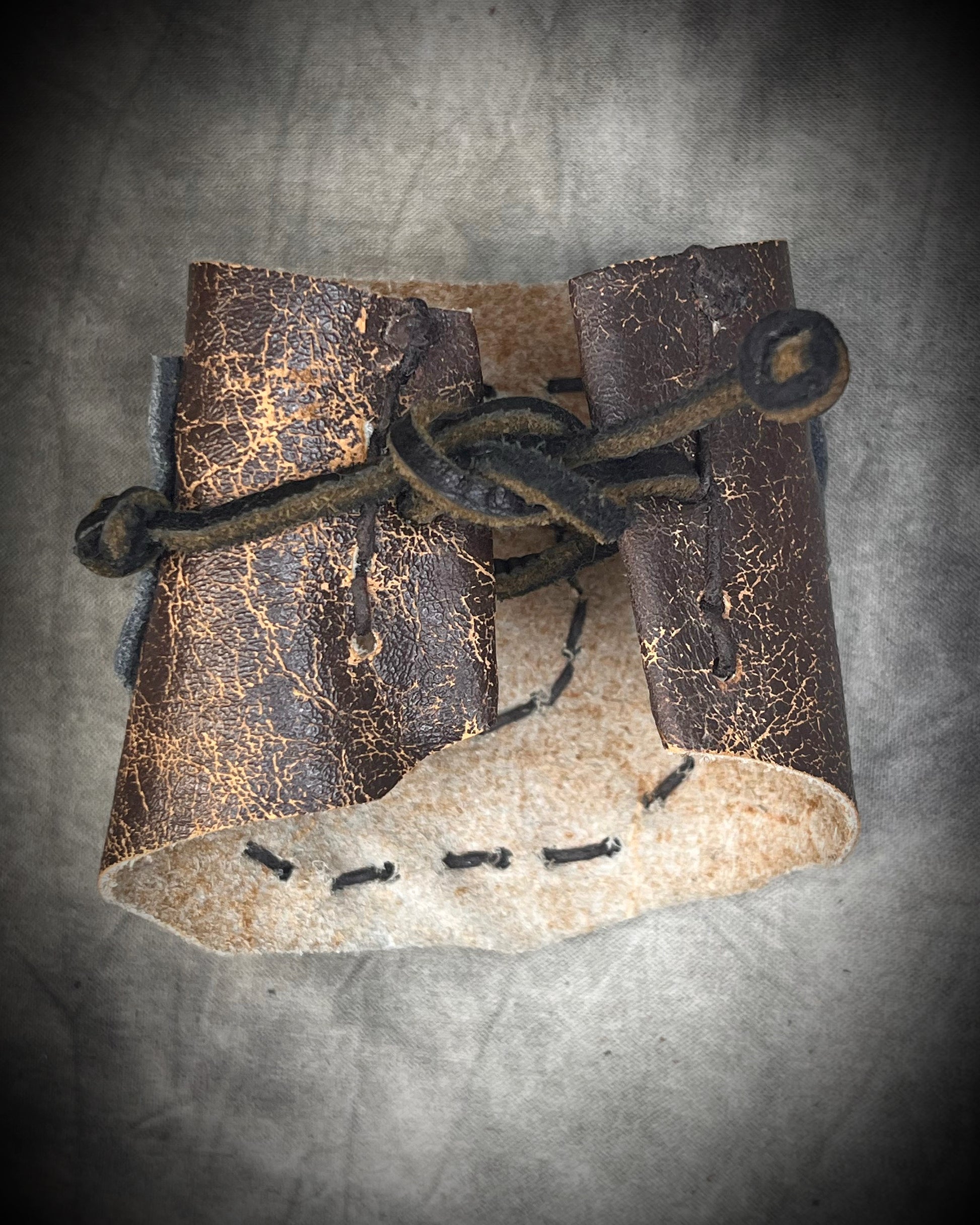 Handmade extra wide 3-inch leather cuff bracelet with layered black and brown leather, brass details, hand stitching, and adjustable leather tie closure by Anothai Hansen.