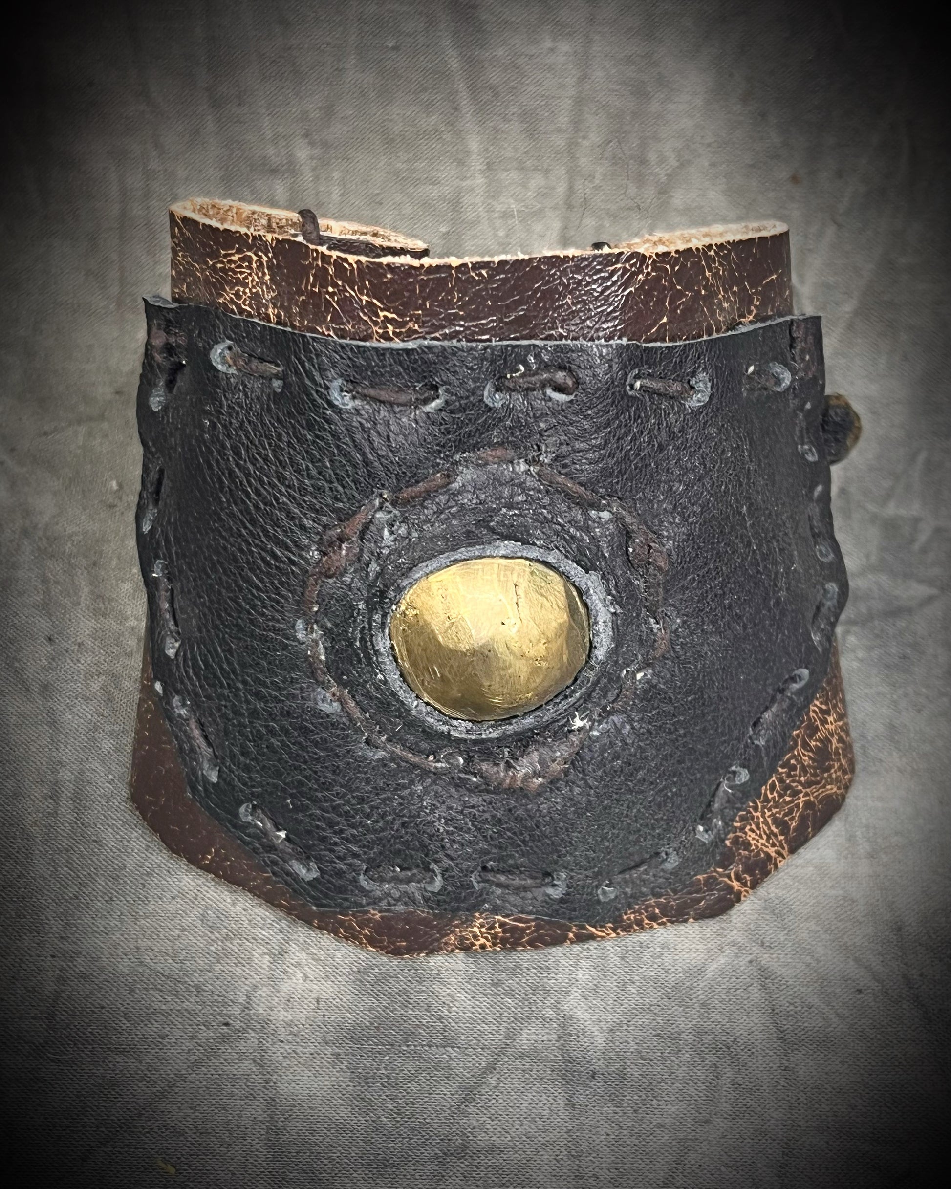 Handmade extra wide 3-inch leather cuff bracelet with layered black and brown leather, brass details, hand stitching, and adjustable leather tie closure by Anothai Hansen.