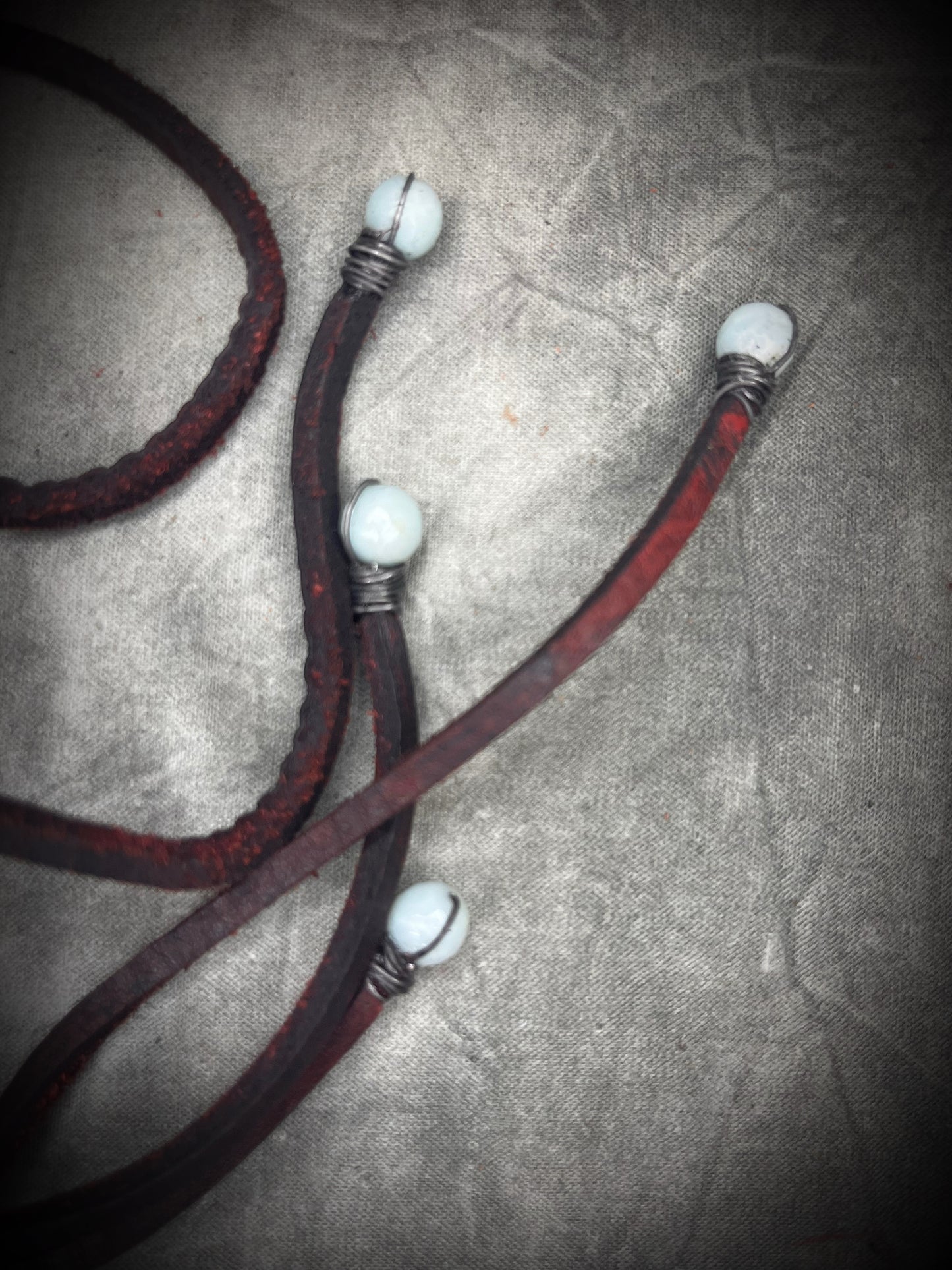 Handmade lapis lazuli slab necklace with aquamarine halo, bloodstone focal stone, deep red leather tie closure, and aquamarine tassel details by Anothai Hansen.