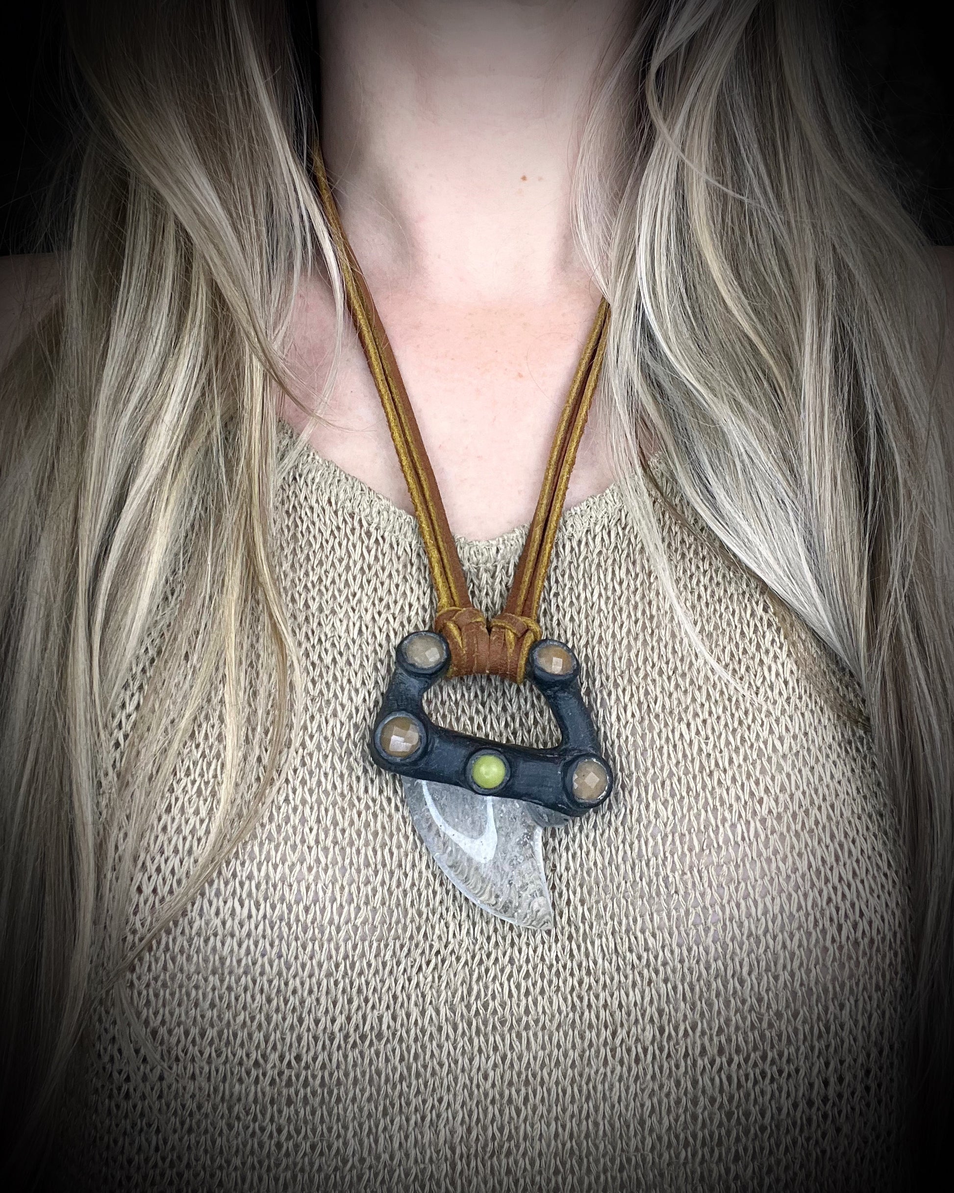 Handmade leather and gemstone pendant by Anothai Hansen featuring a shark tooth shaped quartz crystal accented with warm honey jade and vibrant yellow jade.