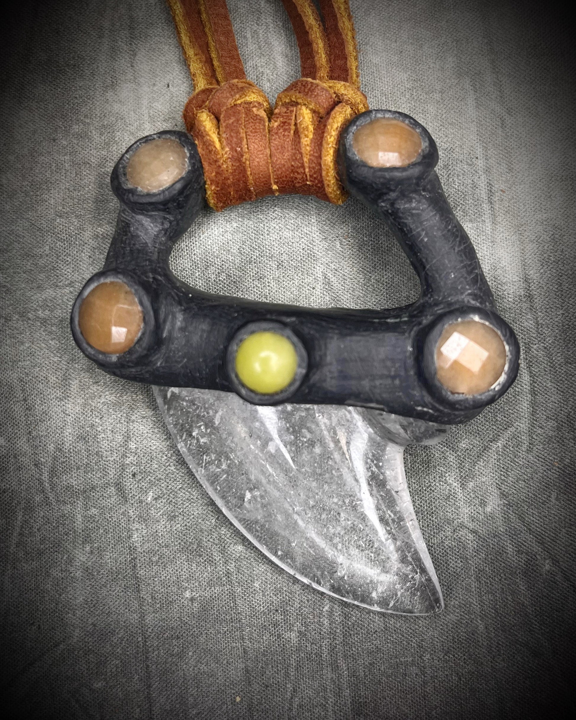 Handmade leather and gemstone pendant by Anothai Hansen featuring a shark tooth shaped quartz crystal accented with warm honey jade and vibrant yellow jade.
