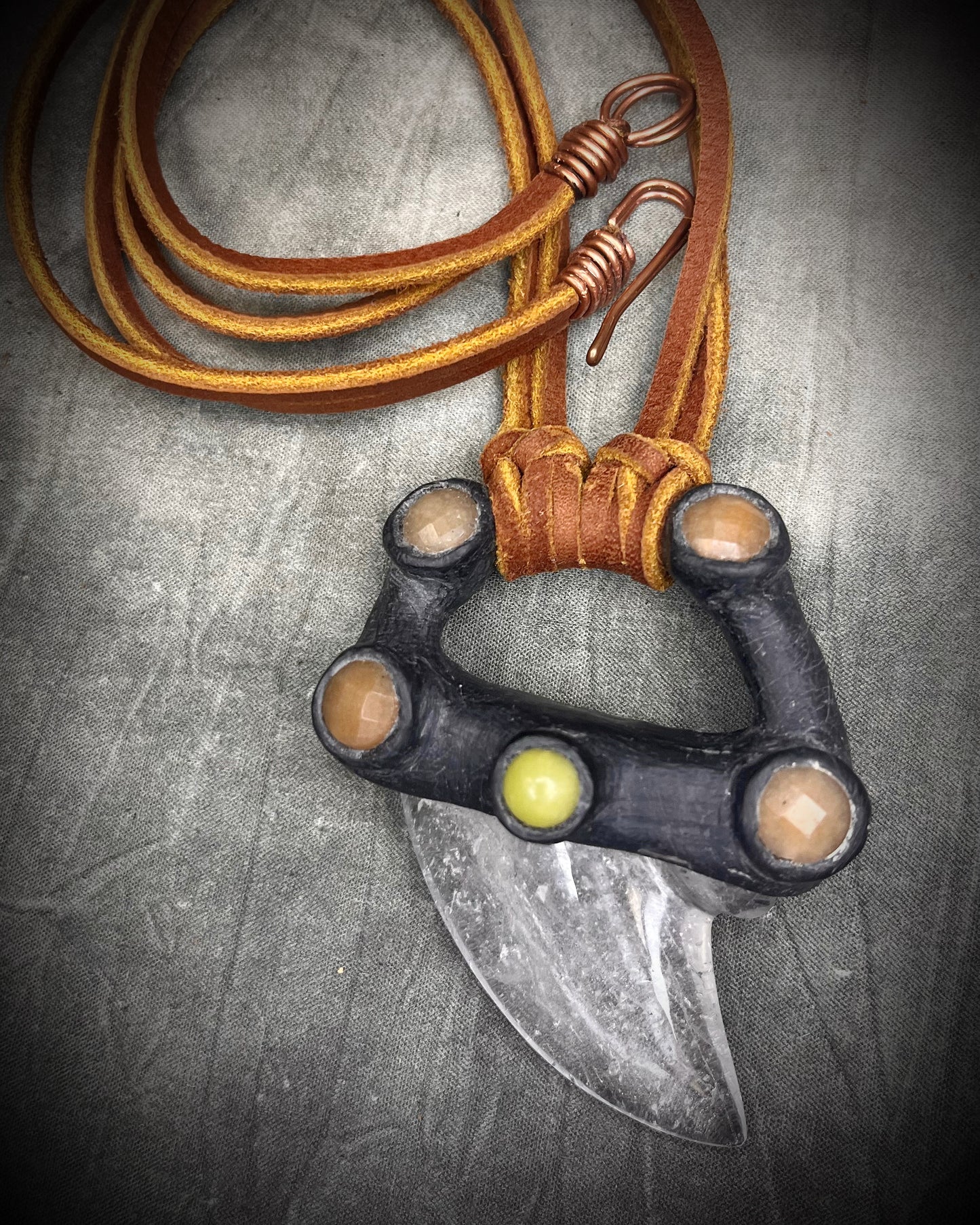 Handmade leather and gemstone pendant by Anothai Hansen featuring a shark tooth shaped quartz crystal accented with warm honey jade and vibrant yellow jade.
