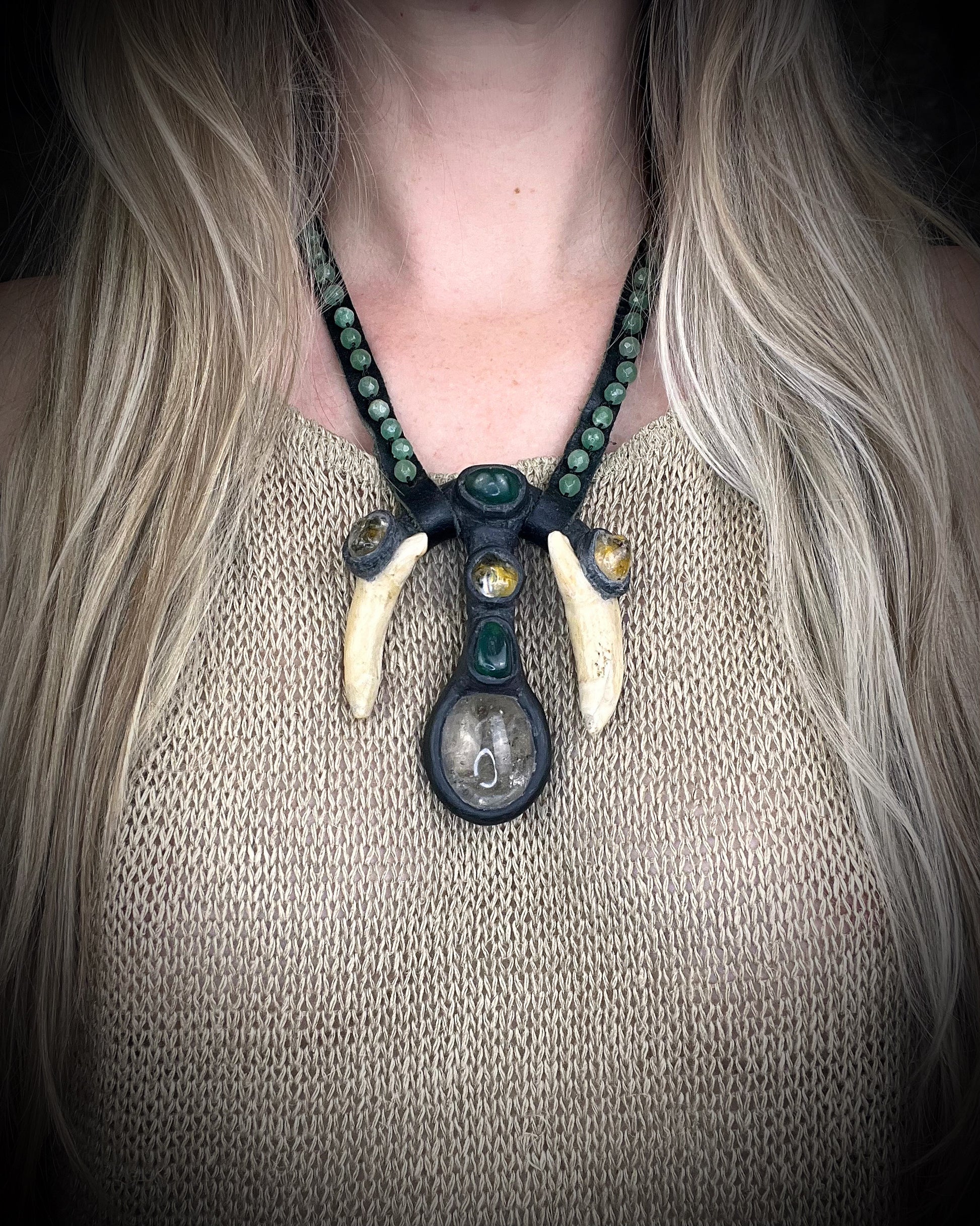 Handmade leather talisman with quartz, bloodstone, citrine, green aventurine, animal teeth, studded leather, and handmade wire clasp by Anothai Hansen.