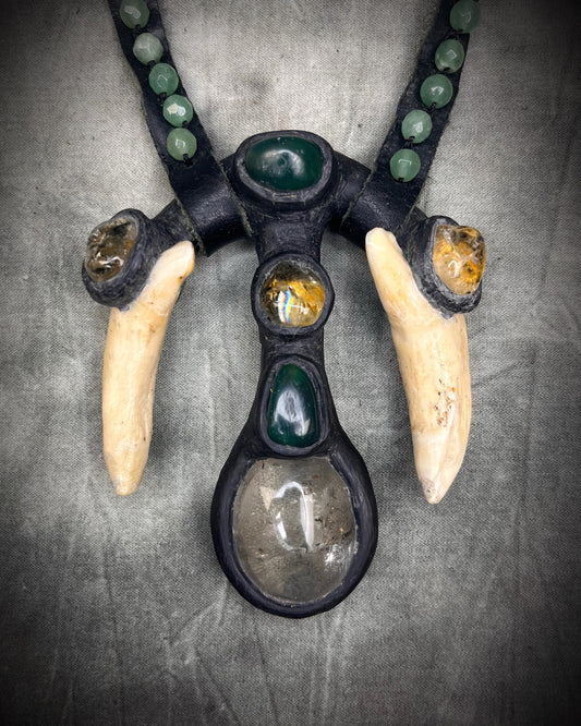 Handmade leather talisman with quartz, bloodstone, citrine, green aventurine, animal teeth, studded leather, and handmade wire clasp by Anothai Hansen.