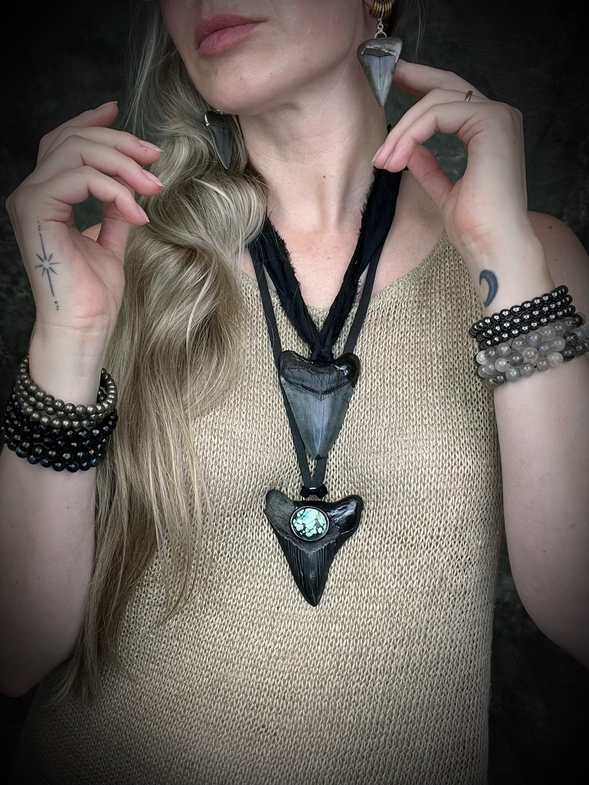 Handmade megalodon tooth talisman with natural turquoise accents, black finish, and black leather cord, featuring a fossilized prehistoric shark tooth transformed into a bold statement necklace.