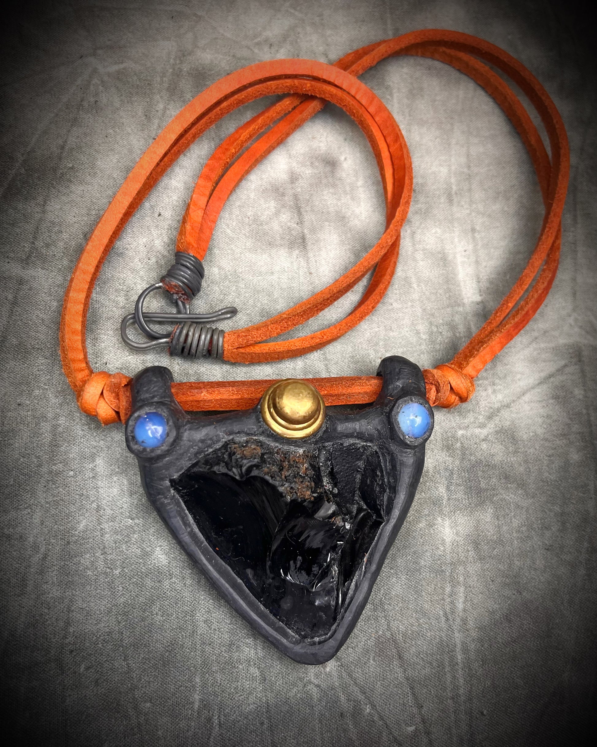 Handmade obsidian pendant with opalite crystals and brass details on orange leather featuring a handmade wire clasp by Anothai Hansen.