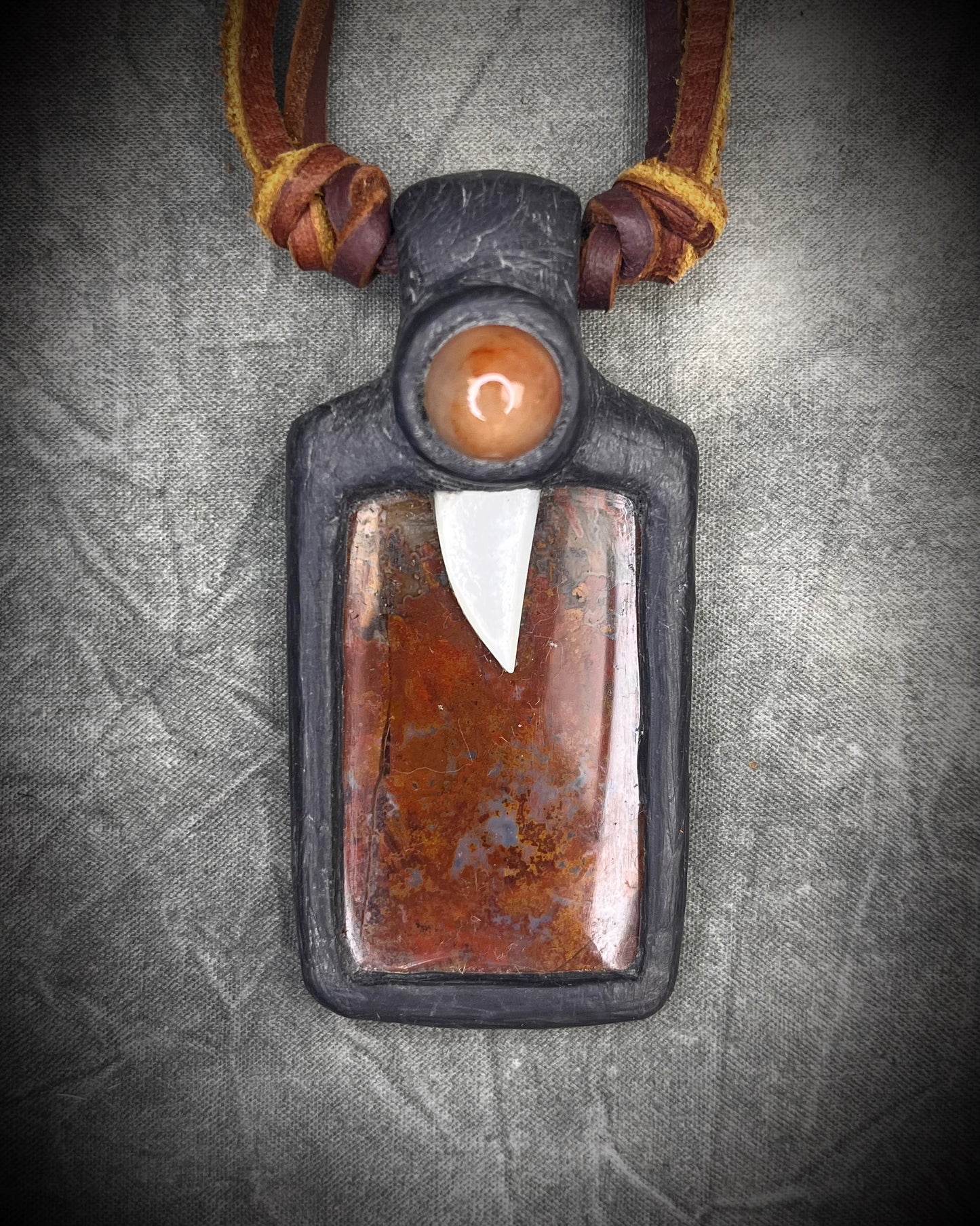
Handmade red agate pendant with carnelian and abalone shell on brown leather featuring a handmade copper-colored wire clasp by Anothai Hansen.