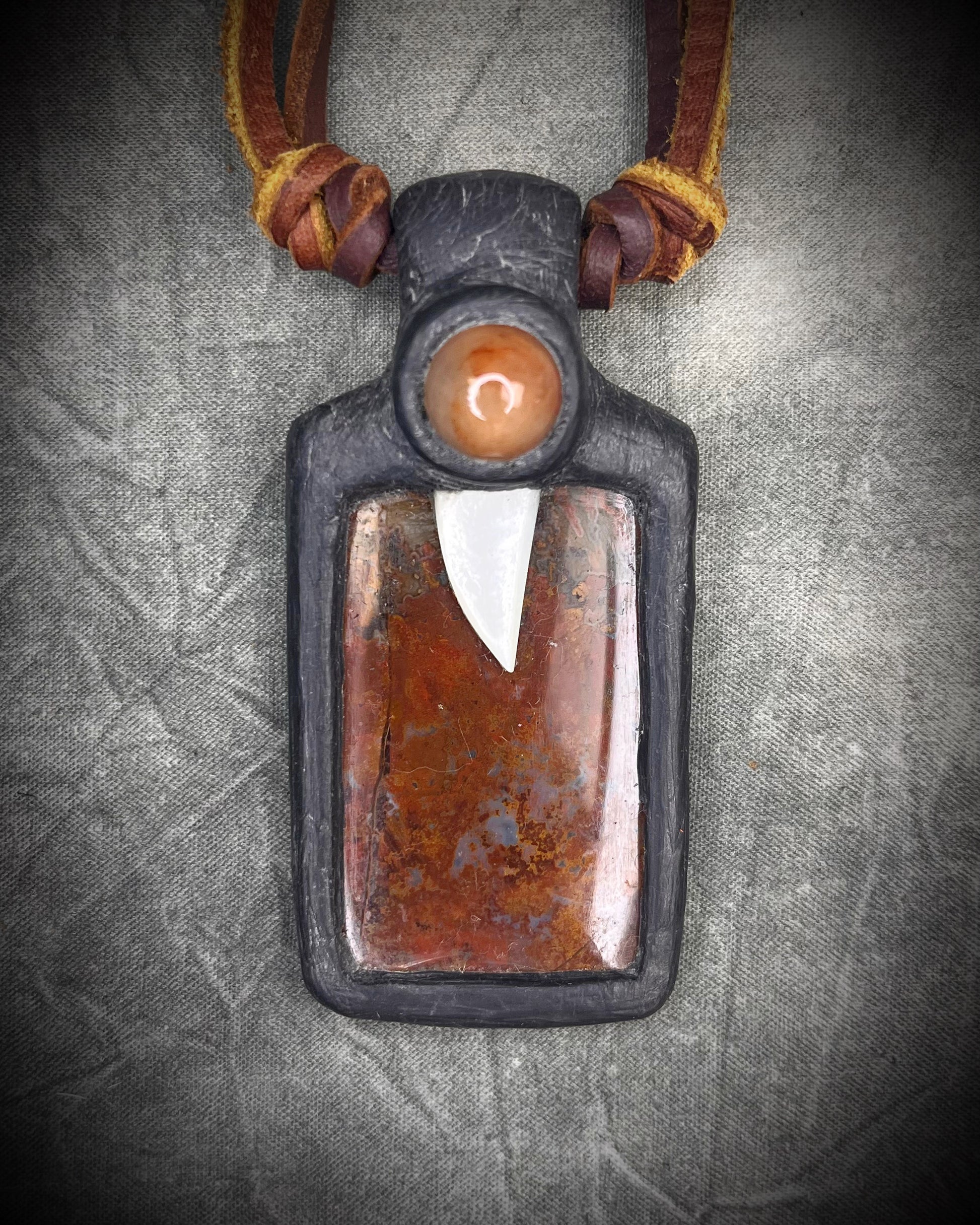
Handmade red agate pendant with carnelian and abalone shell on brown leather featuring a handmade copper-colored wire clasp by Anothai Hansen.