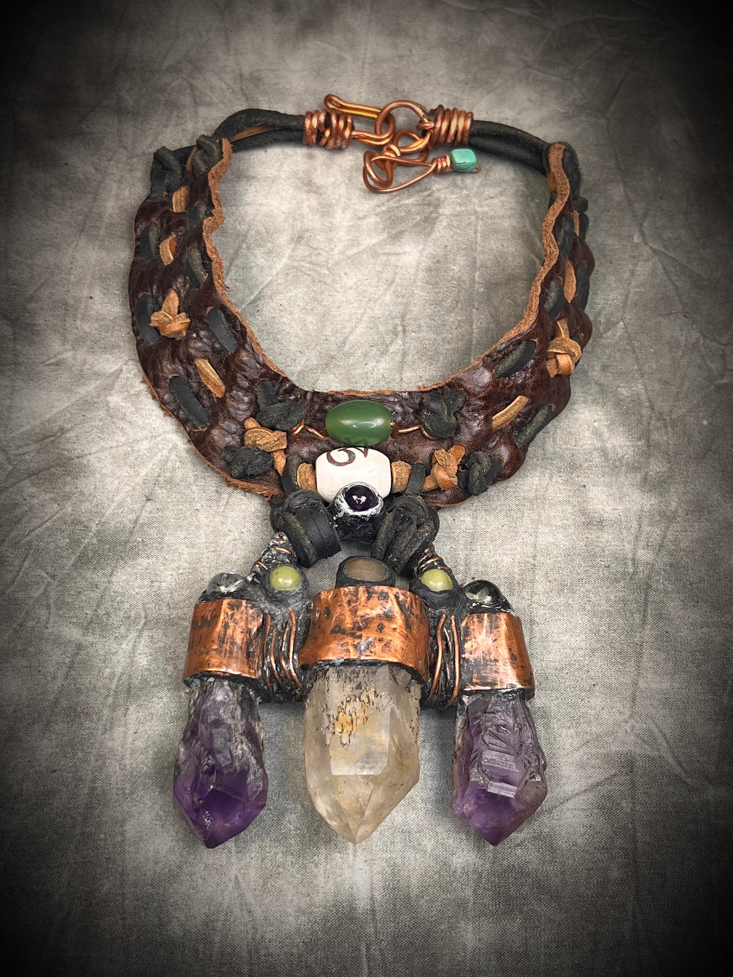 Handmade trident leather choker with quartz point, amethyst points, yellow jade, brass details, and copper wire clasp by Anothai Hansen.