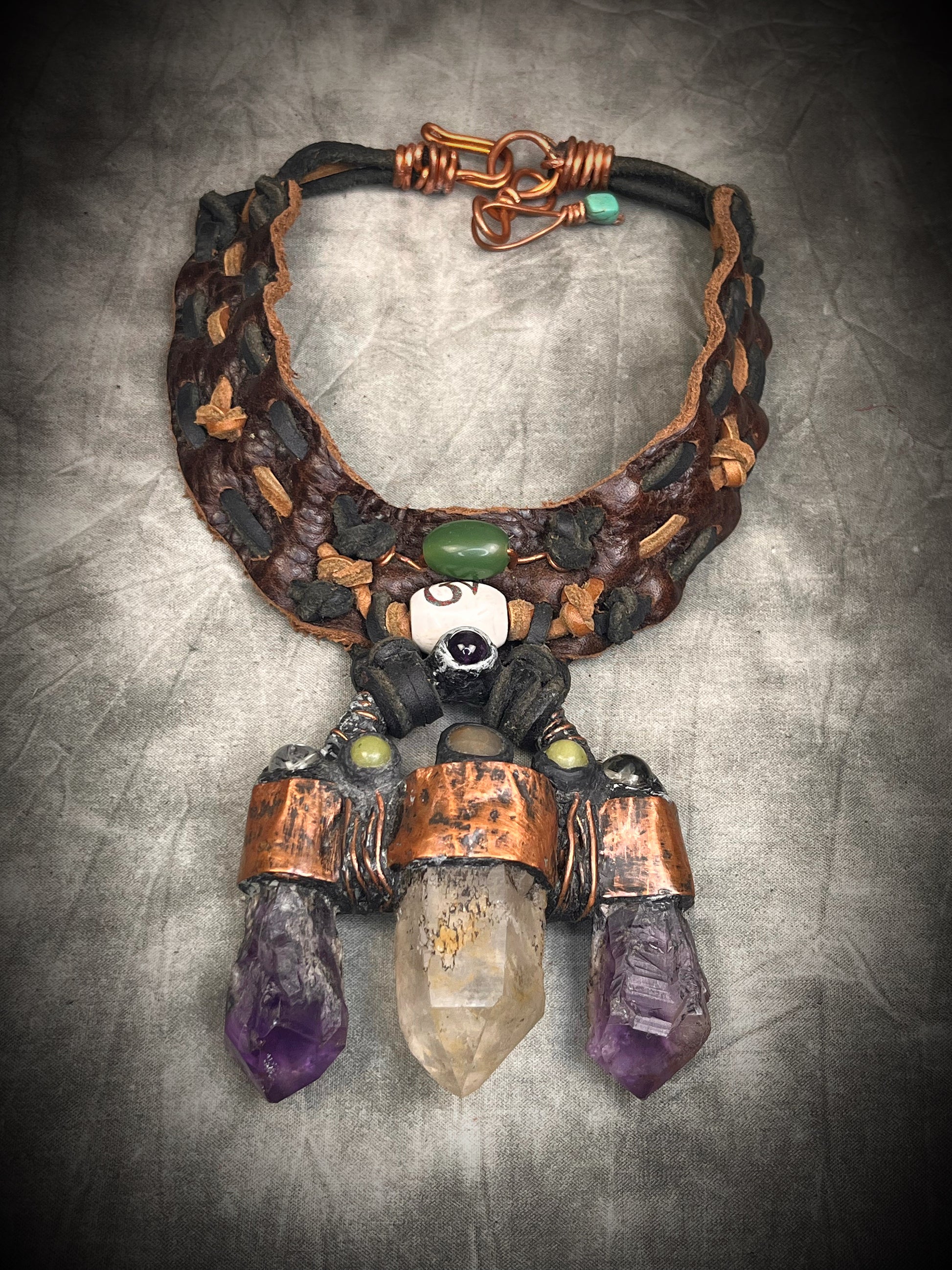 Handmade trident leather choker with quartz point, amethyst points, yellow jade, brass details, and copper wire clasp by Anothai Hansen.