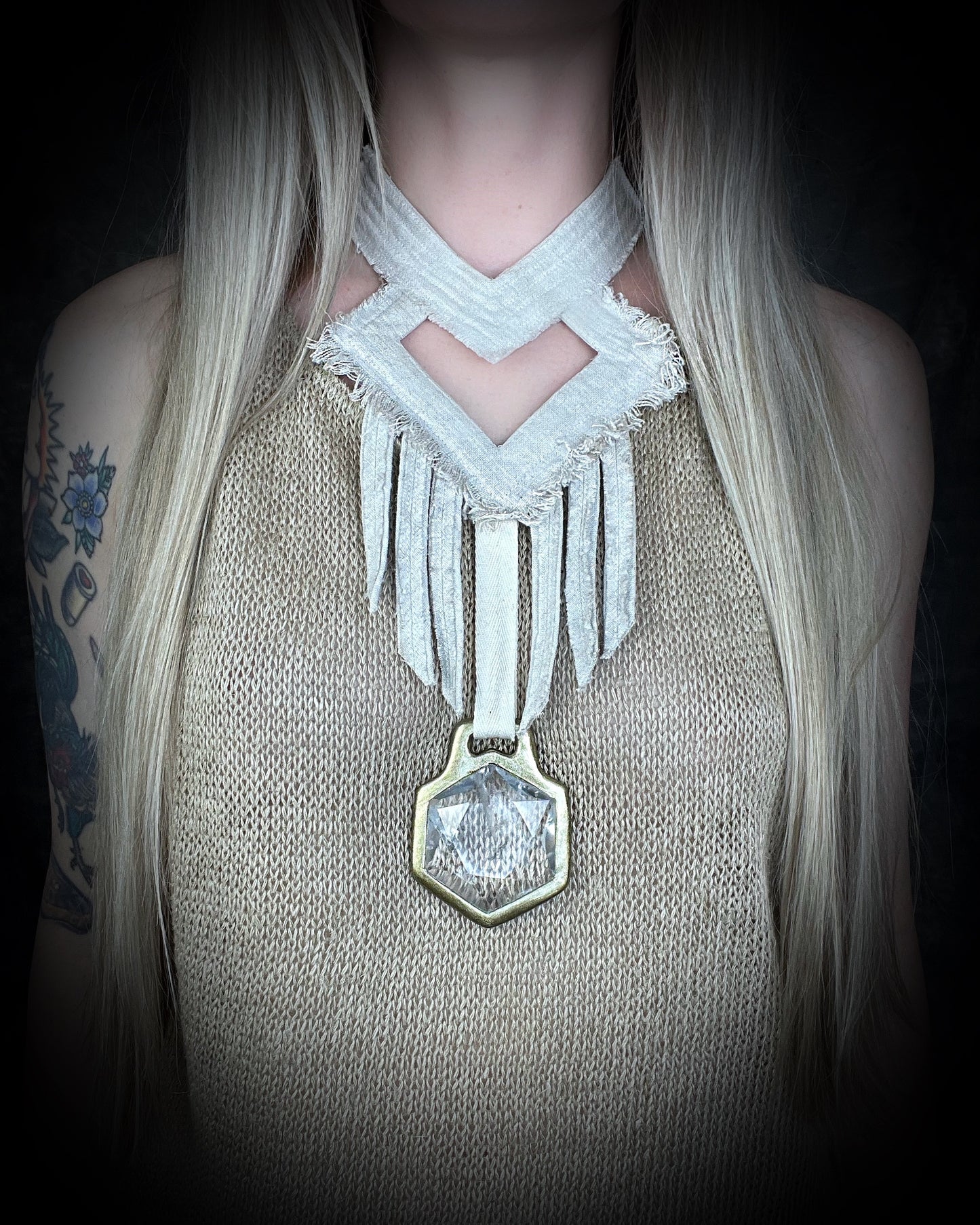 Worn on a woman with blond hair and a natural fiber top, a handmade raw linen choker statement style necklace featuring a handcrafted quartz star of david hexagon crystal and geometric shapes and fringe.  Wearable art for a boho free spirit or festival jewelry!