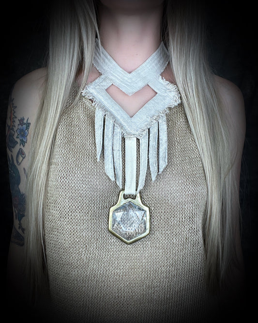 Worn on a woman with blond hair and a natural fiber top, a handmade raw linen choker statement style necklace featuring a handcrafted quartz star of david hexagon crystal and geometric shapes and fringe.  Wearable art for a boho free spirit or festival jewelry!