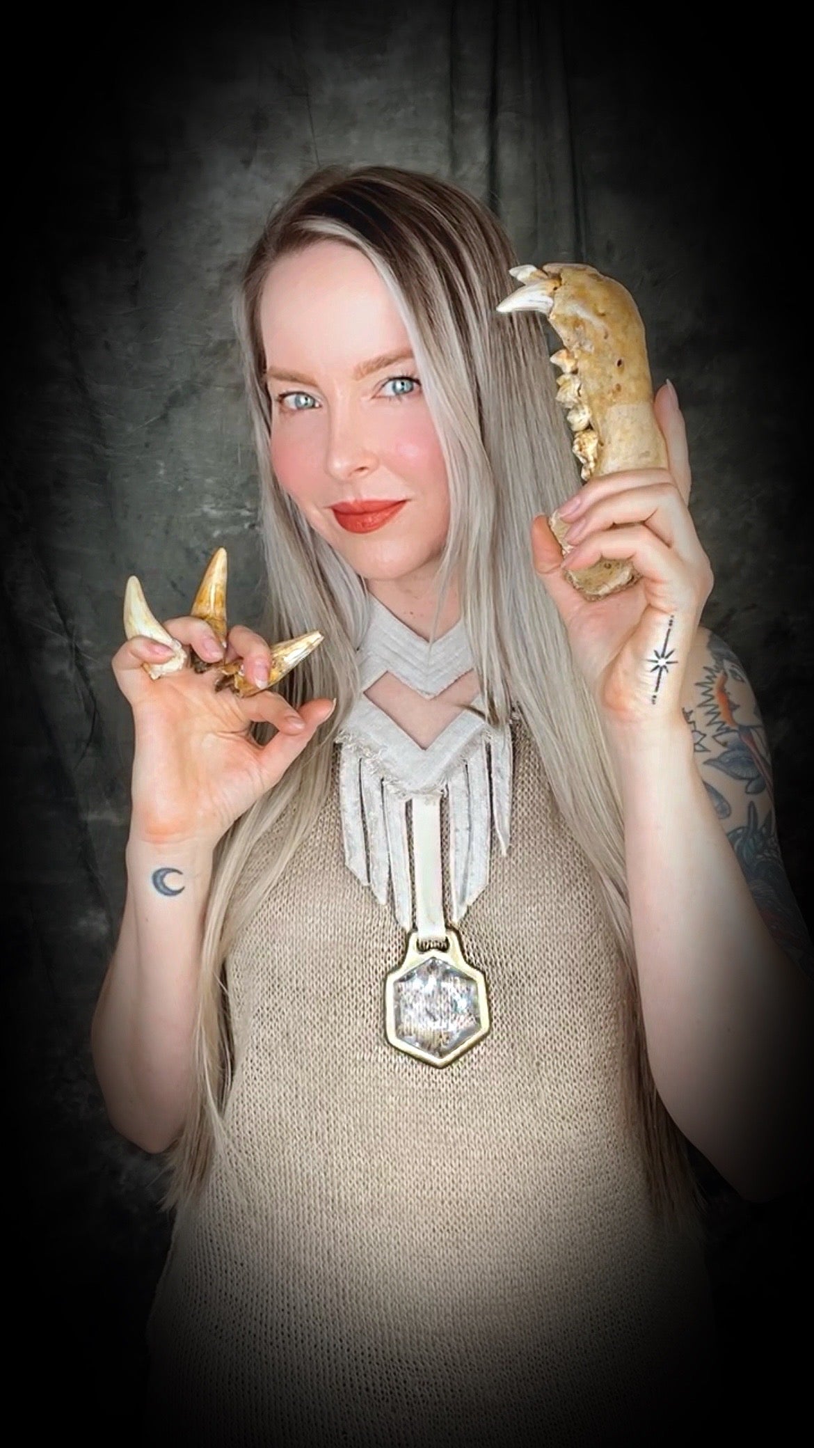 Worn on a woman with blond hair holding fossils and a natural fiber top, a handmade raw linen choker statement style necklace featuring a handcrafted quartz star of david hexagon crystal and geometric shapes and fringe.  Wearable art for a boho free spirit or festival jewelry!