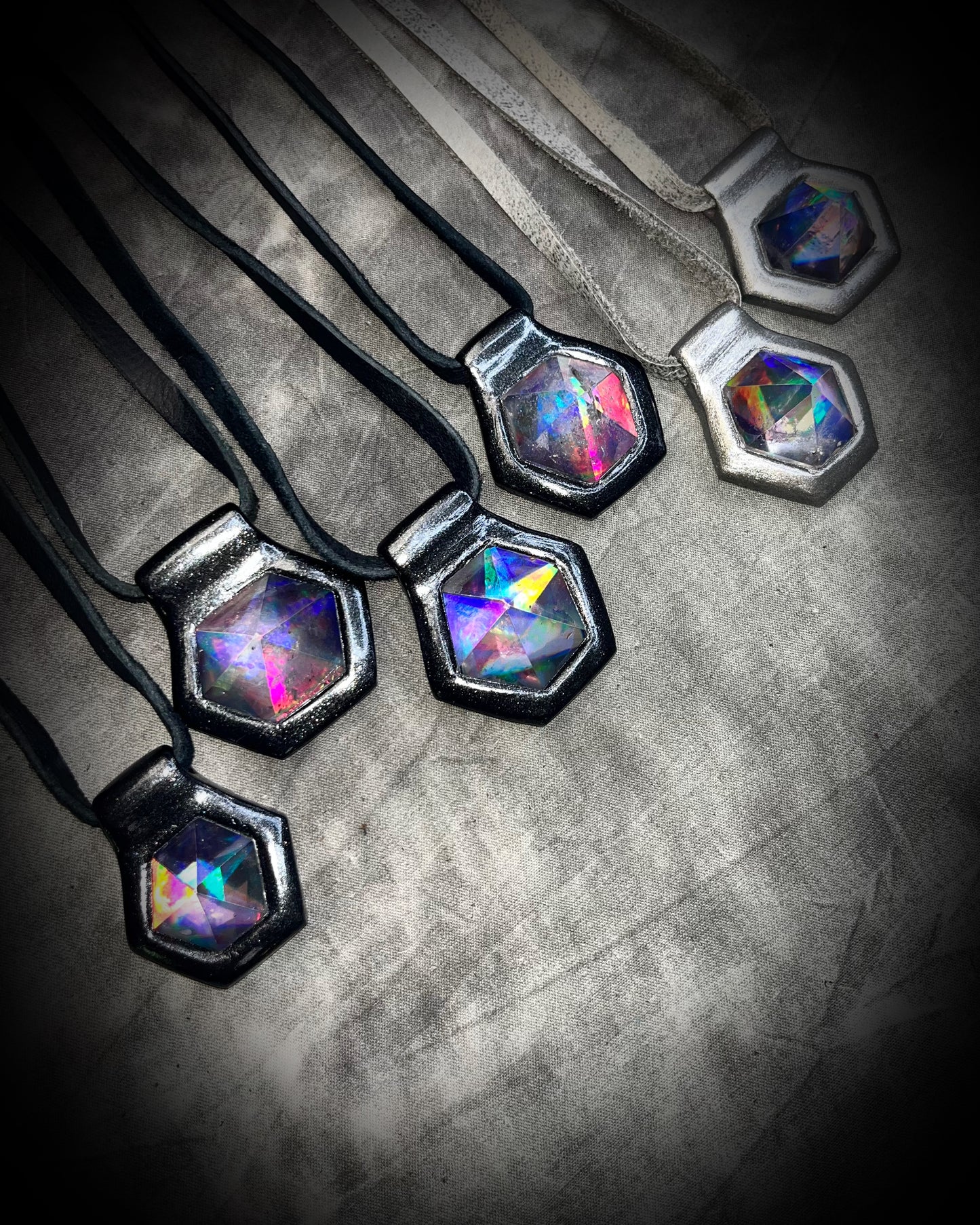 Multiple David Bowie inspired glam handmade designer quartz crystal black rainbow pendants. Black finish on black leather and gunmetal finish on silver leather. Queer, Transgender, Non-Binary jewelry!