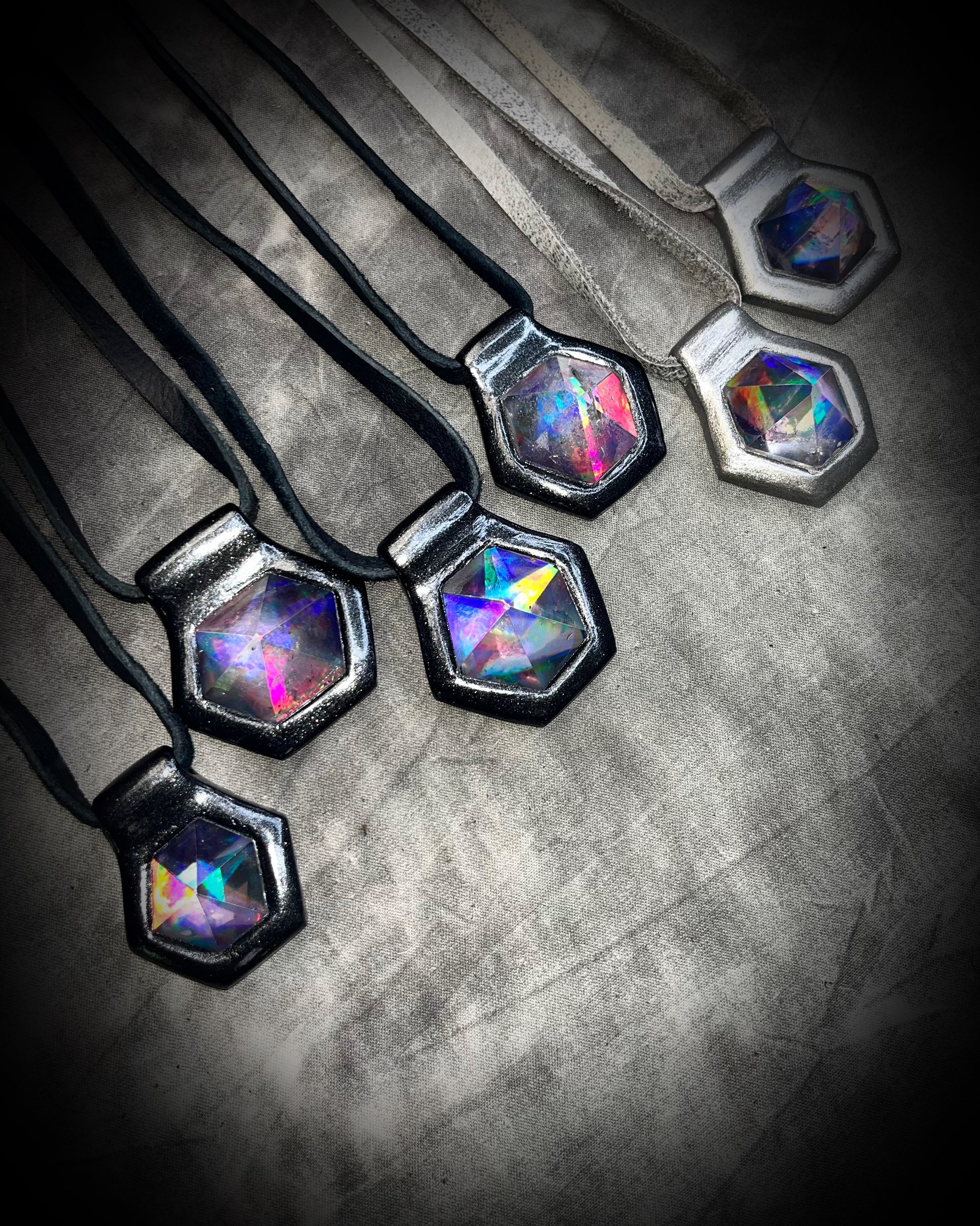 Multiple David Bowie inspired glam handmade designer quartz crystal black rainbow pendants. Black finish on black leather and gunmetal finish on silver leather. Queer, Transgender, Non-Binary jewelry!