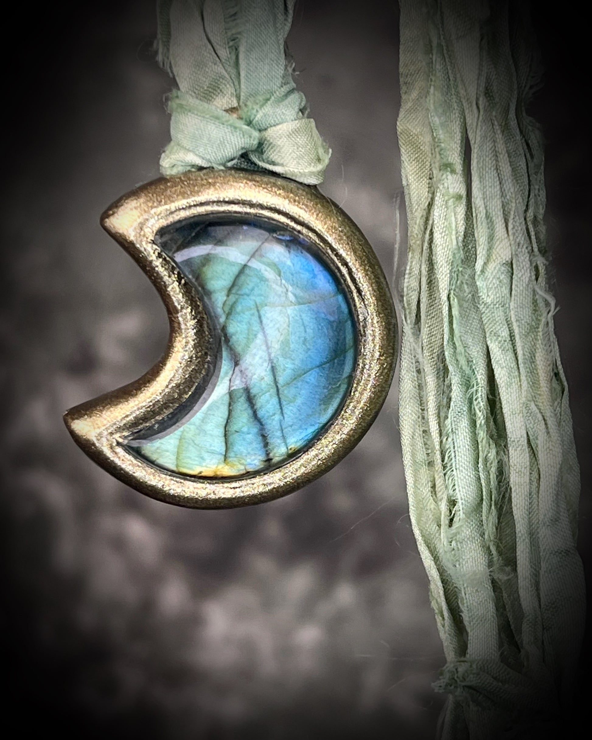 Labradorite moon talisman with high natural flash, sculpted gold finish, and aqua green recycled silk ties by Become Spellbound.