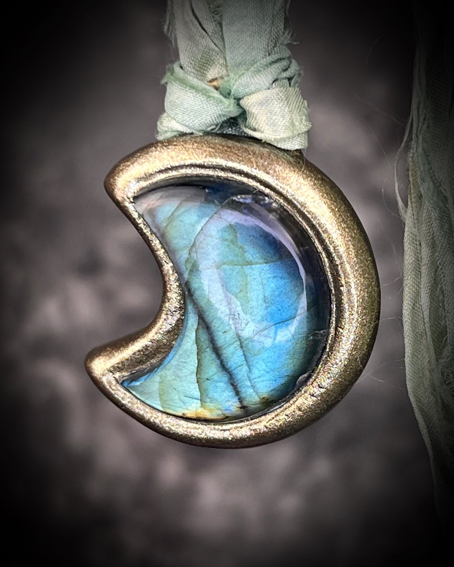 Labradorite moon talisman with high natural flash, sculpted gold finish, and aqua green recycled silk ties by Become Spellbound.