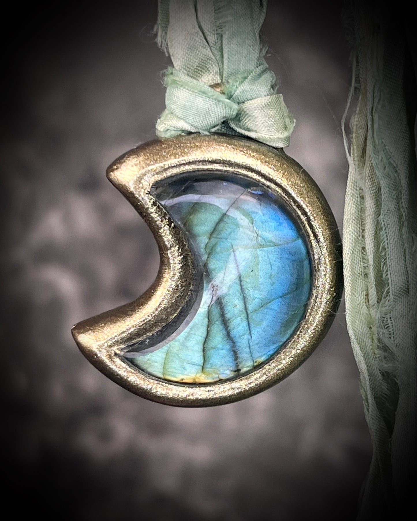 Labradorite moon talisman with high natural flash, sculpted gold finish, and aqua green recycled silk ties by Become Spellbound.