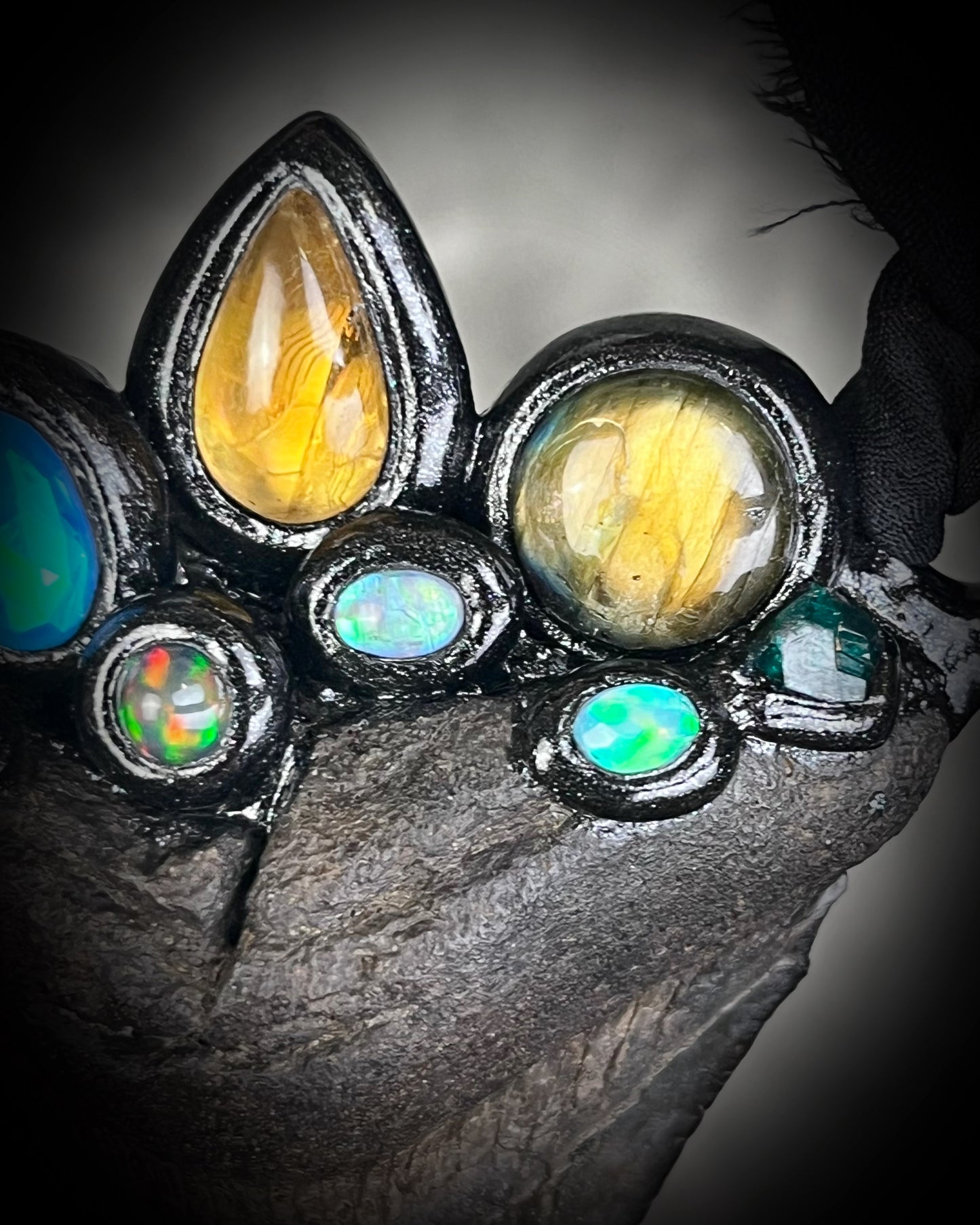 Large megalodon tooth necklace crowned with citrine, opal, black opal, labradorite, dioptase, golden tourmaline, lapis lazuli, and moonstone — set in black and hung from recycled silk ribbons.