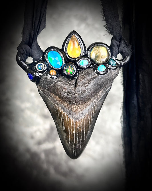 Large megalodon tooth necklace crowned with citrine, opal, black opal, labradorite, dioptase, golden tourmaline, lapis lazuli, and moonstone — set in black and hung from recycled silk ribbons