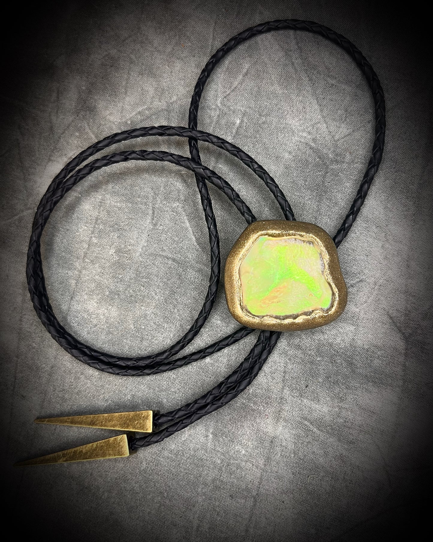 Libyan Desert Glass bolo tie with sculpted gold finish, black leather cord, and gold spike bolo tips by Become Spellbound, Baltimore Magazine Best of Baltimore 2026 Jewelry winner.