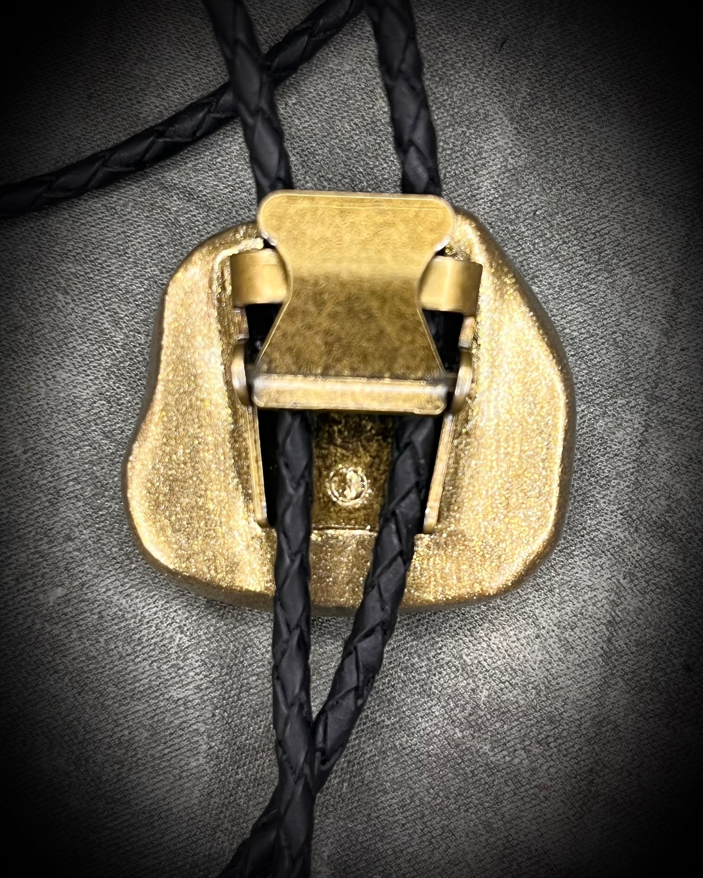 Libyan Desert Glass bolo tie with sculpted gold finish, black leather cord, and gold spike bolo tips by Become Spellbound, Baltimore Magazine Best of Baltimore 2026 Jewelry winner.