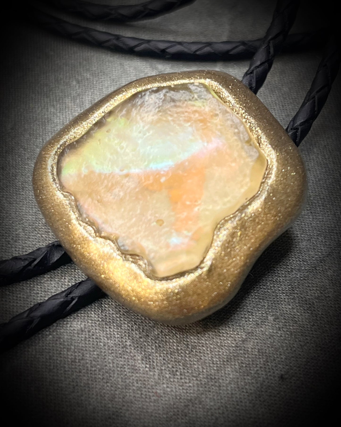 Libyan Desert Glass bolo tie with sculpted gold finish, black leather cord, and gold spike bolo tips by Become Spellbound, Baltimore Magazine Best of Baltimore 2026 Jewelry winner.