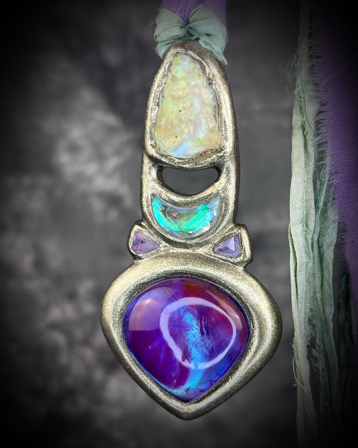 Libyan Desert Glass talisman with amethyst, prasiolite and lavender spinel on recycled silk, featuring shifting green, gold, pink and purple glow. Handmade by Become Spellbound.
