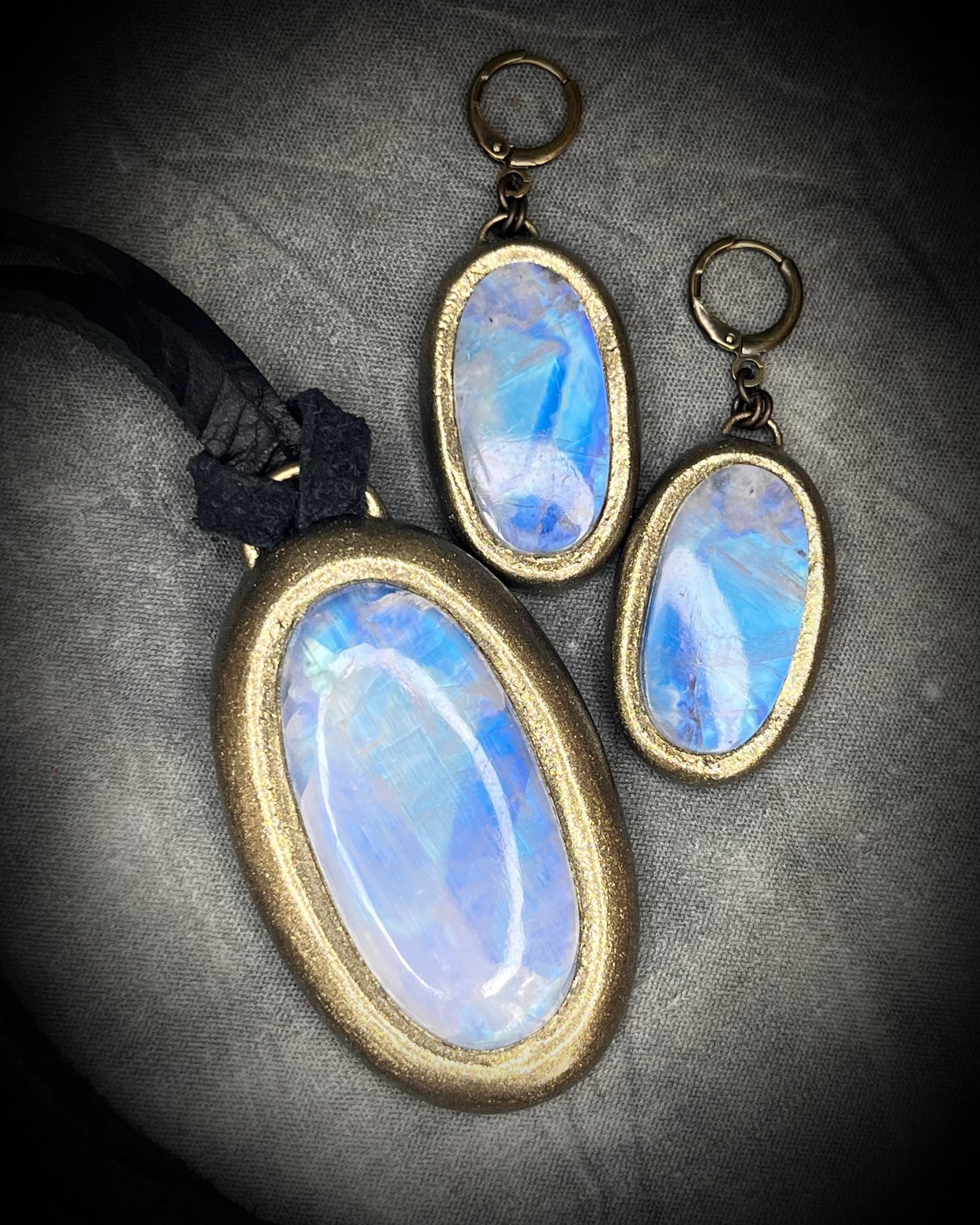 Luminous flashy rainbow moonstone earrings in gold finish hung from hypoallergenic brass huggie earring hooks. Shown here with matching rainbow moonstone necklace on black leather cord. Goddess gift set for her.