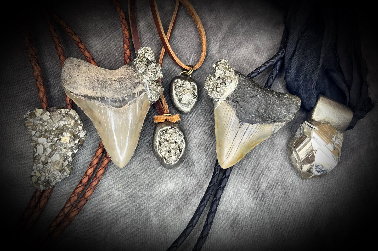 Mineral and fossil pendants on leather cords against a dark background
