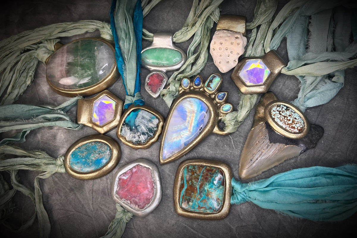 Collection of colorful gemstone and fossil necklaces hung from sea green recycled silk, all a part of Become Spellbound's Megalodon Relics collection- handmade in Baltimore.