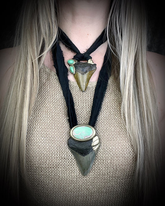 Necklace with shark tooth and turquoise stone pendant on a person wearing a beige sweater.