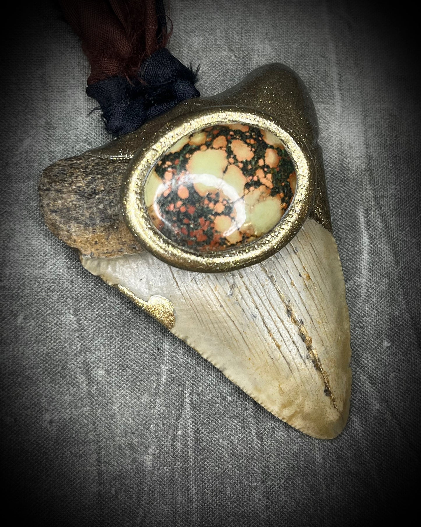 Megalodon fossil tooth talisman with earth-toned turquoise in moss green, orange and burgundy-red, gold finish, and black and brown recycled silk.
