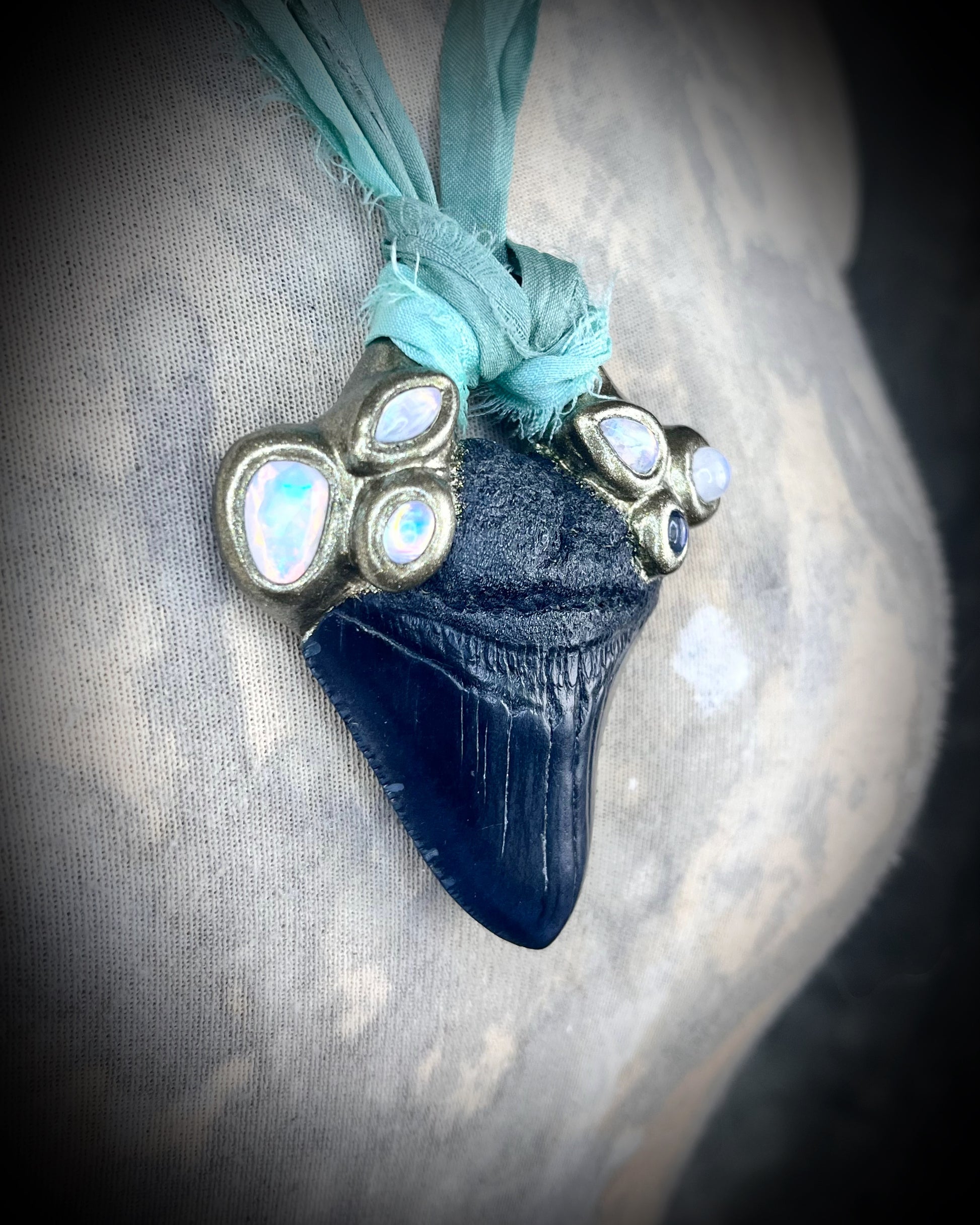 Megalodon shark tooth fossil handcrafted crystal talisman featuring opal gemstone and rainbow moonstones in gold, hung from recycled aqua silk. Beach wedding or summer jewelry photoshoot, cosplay, fantasy film costume or everyday enchantment!