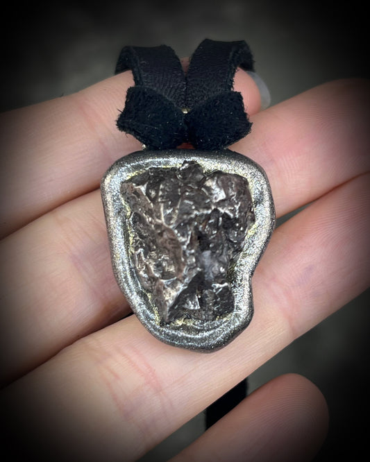 Meteorite talisman in gunmetal finish on black leather, cosmic statement jewelry handmade by Become Spellbound in Baltimore, Maryland.
