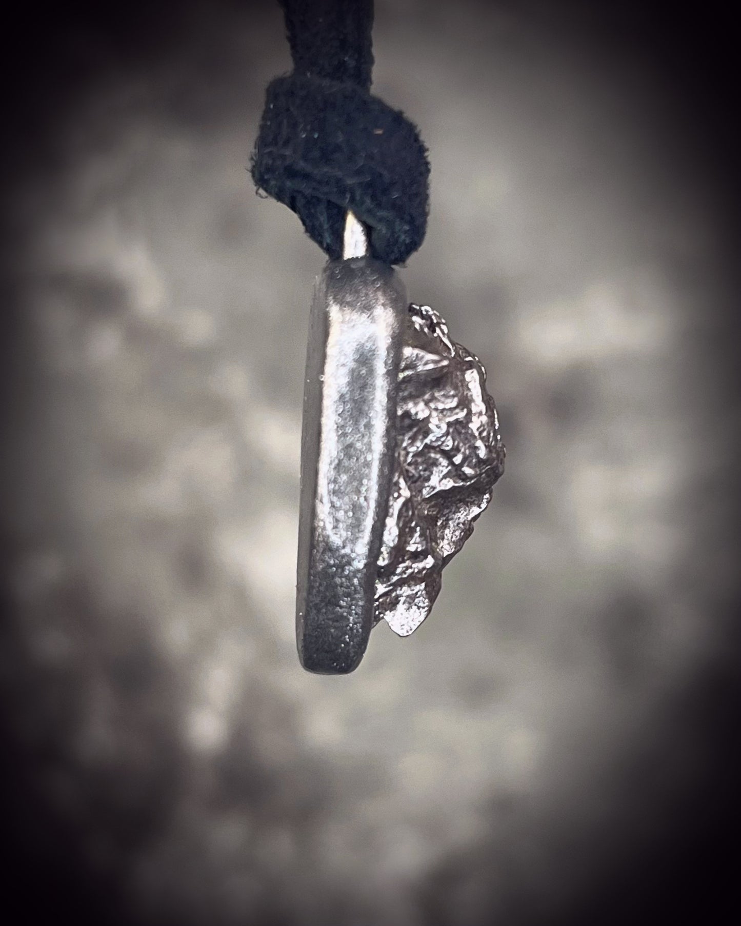 Meteorite talisman in gunmetal finish on black leather, cosmic statement jewelry handmade by Become Spellbound in Baltimore, Maryland.
