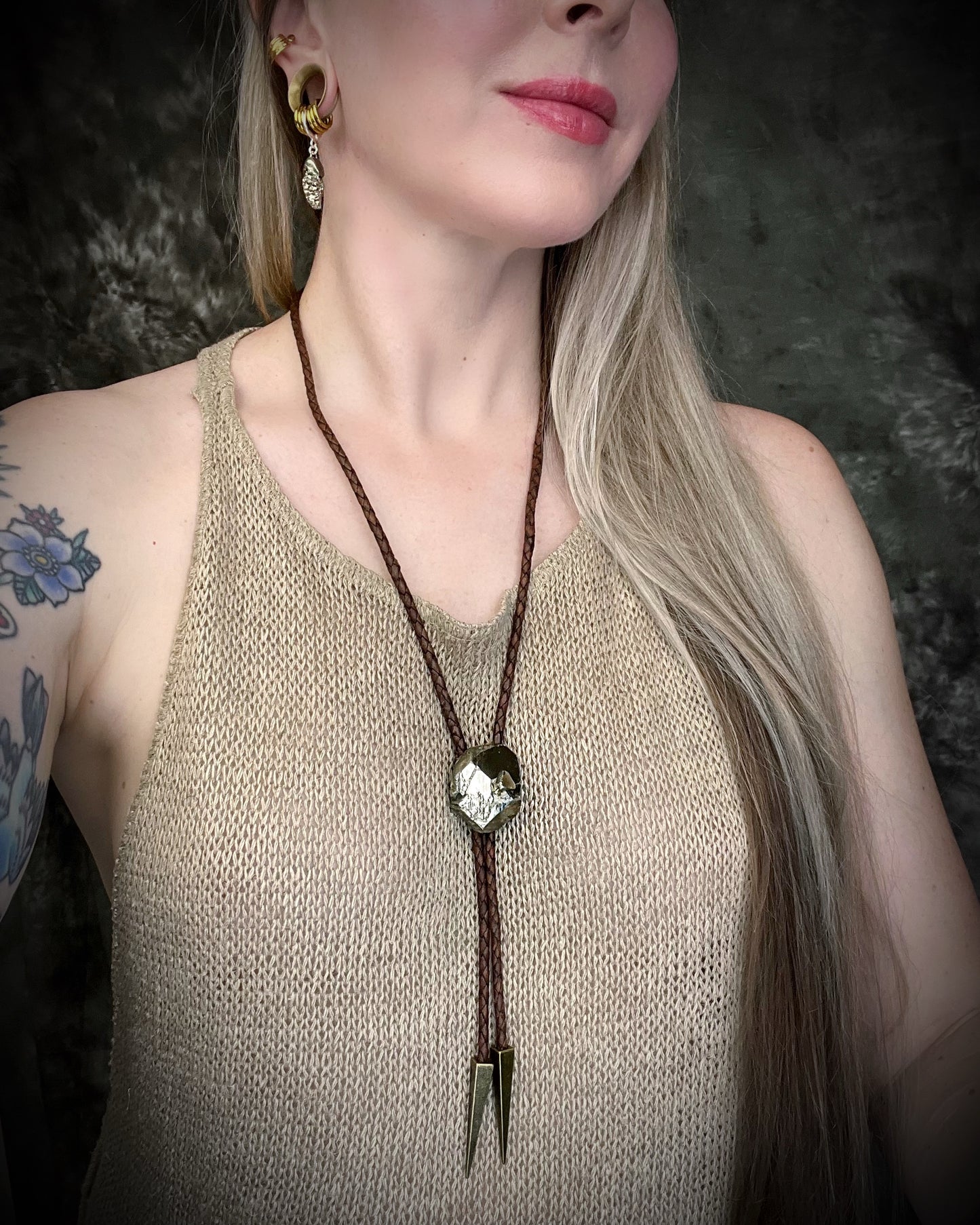 Model wearing Raw Pyrite gemstone Bolo tie set in an invisible finish and mounted on earthy brown leather. A talisman for ambition, success, and manifestation. Western 2026 jewelry trend bolo. 