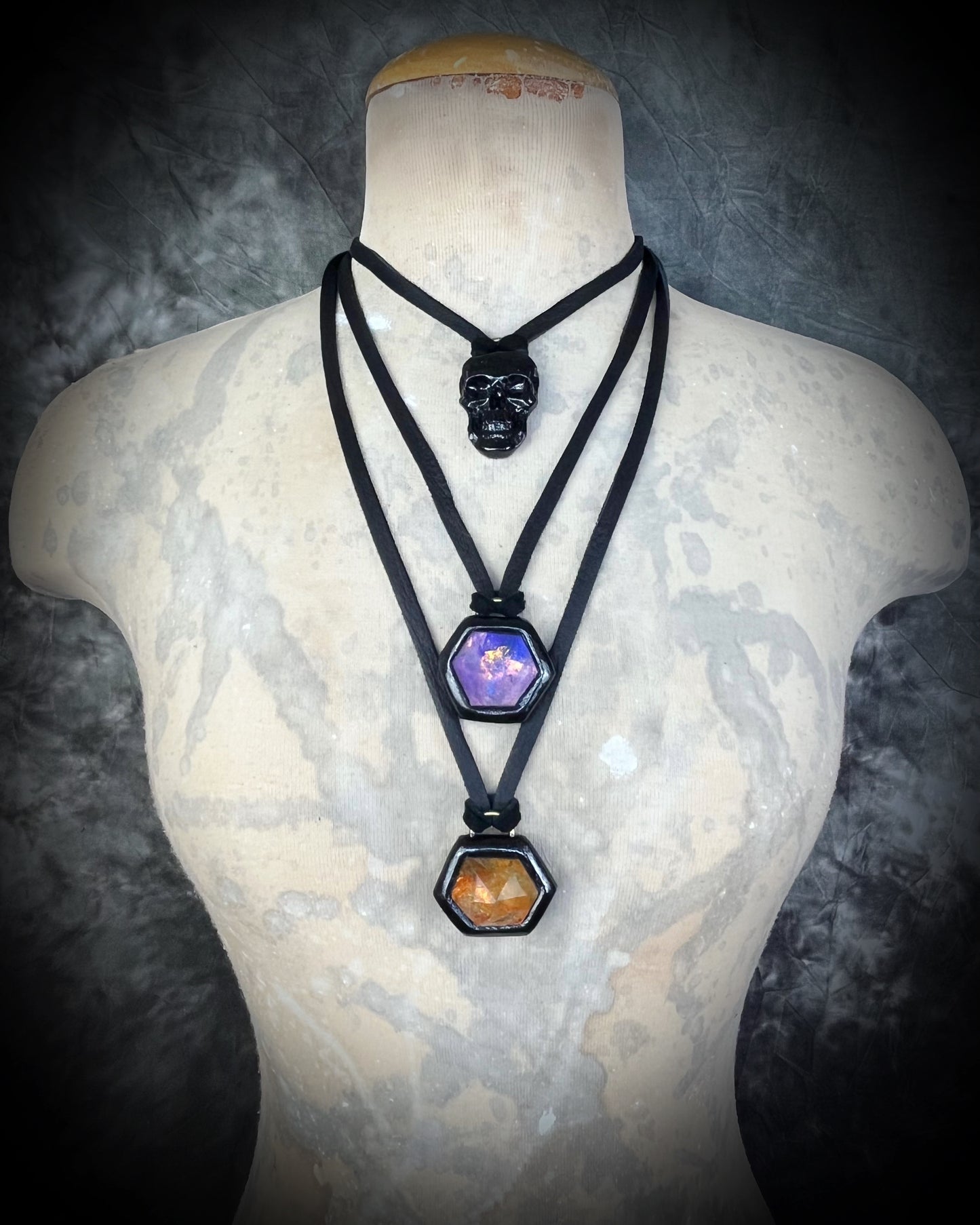 Model wearing black-framed amethyst and fire citrine hexagon pendants on black leather — gothic mystical crystal jewelry layered for a bold look.