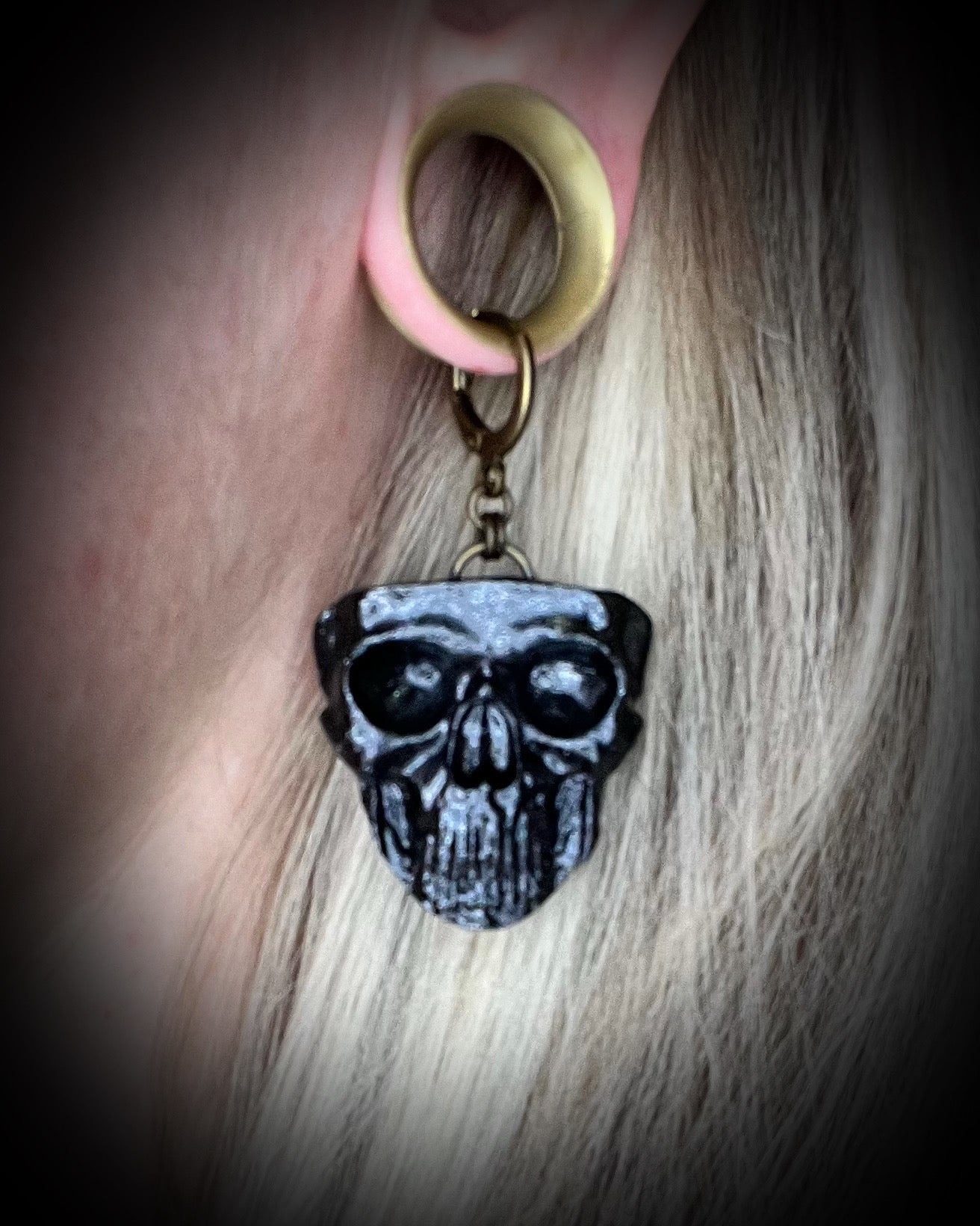 Model wearing sculptural black skull earrings on brass hooks — bold gothic statement jewelry for spooky season.