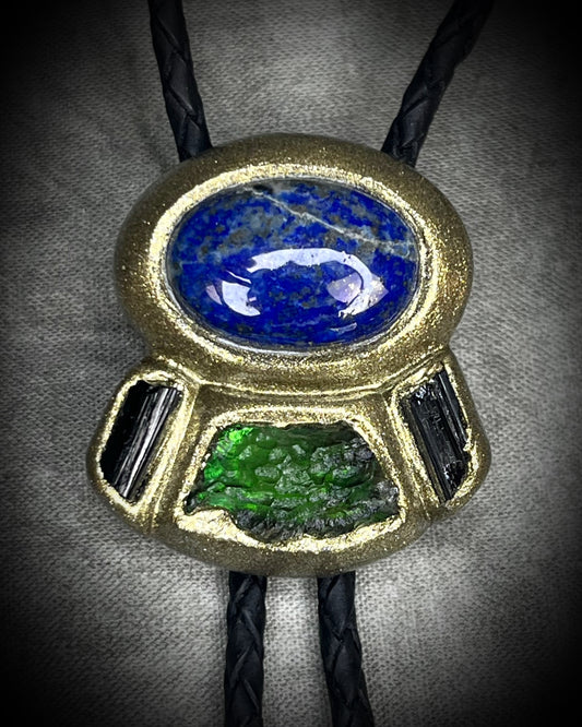 Moldavite bolo tie with lapis lazuli and black tourmaline on black leather, featuring gold finish and spike bolo tips, handmade by Become Spellbound.