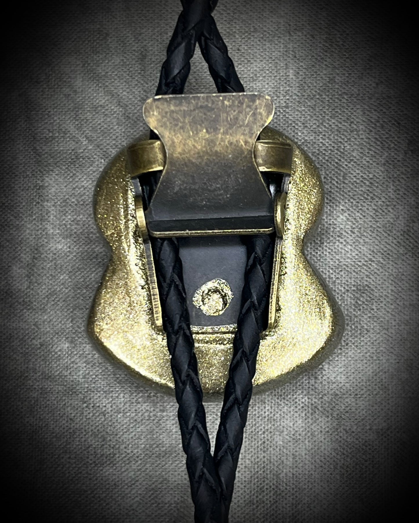 Moldavite bolo tie with lapis lazuli and black tourmaline on black leather, featuring gold finish and spike bolo tips, handmade by Become Spellbound.