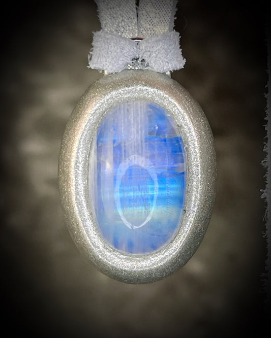 Moonstone pendant in silver finish with a reflective luminous surface hung from silver leather on a dark background