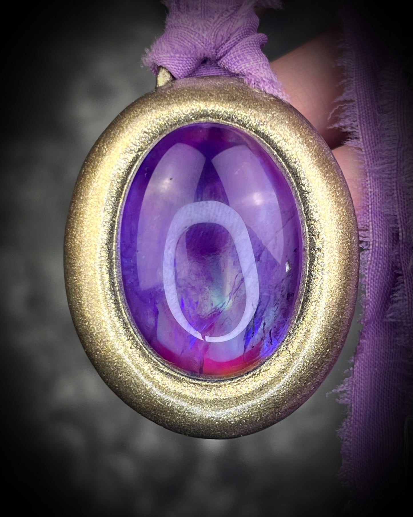 Mystical amethyst talisman with soft nebula glow, sculpted gold finish, and lilac recycled silk ties by Become Spellbound.
