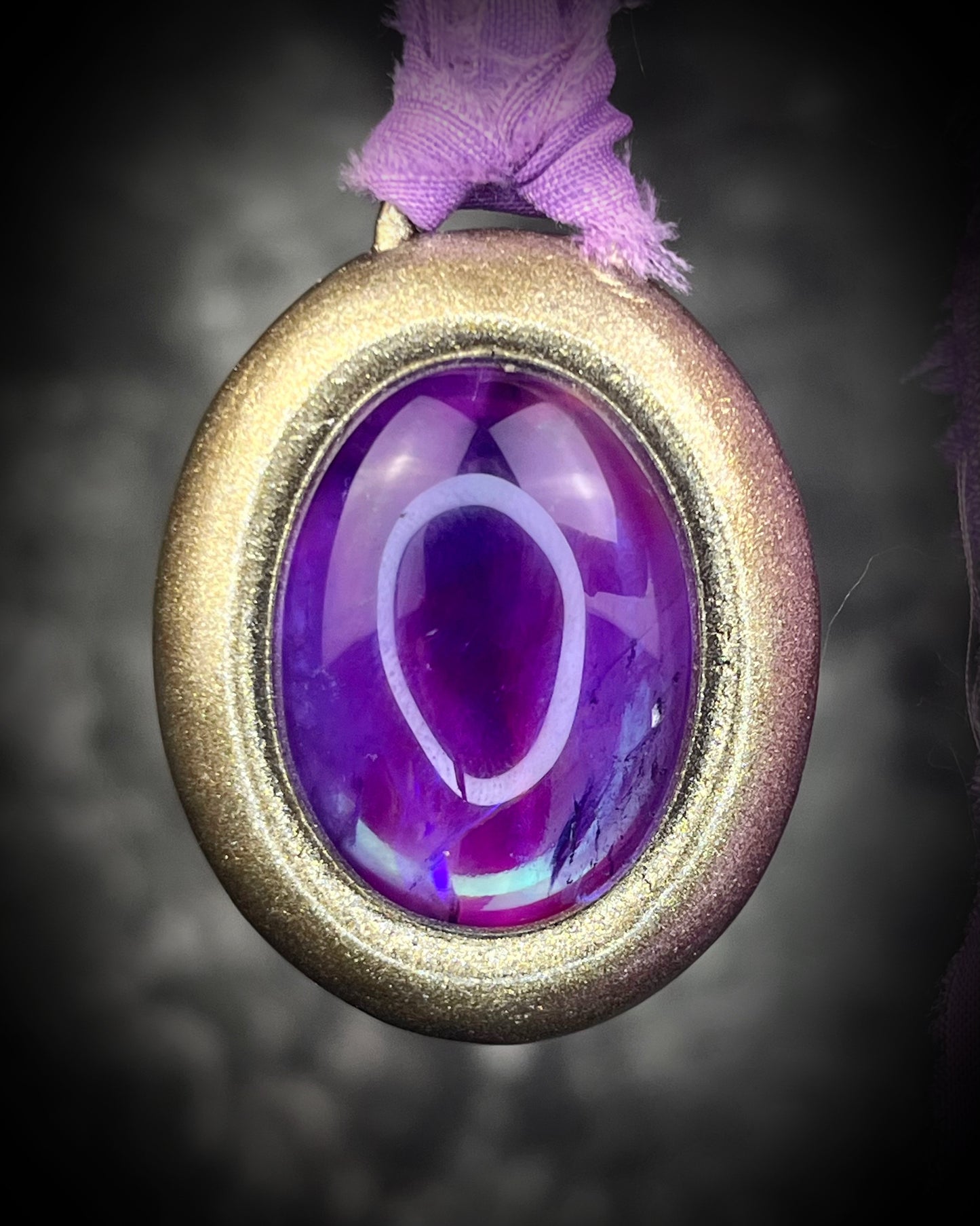 Mystical amethyst talisman with soft nebula glow, sculpted gold finish, and lilac recycled silk ties by Become Spellbound.