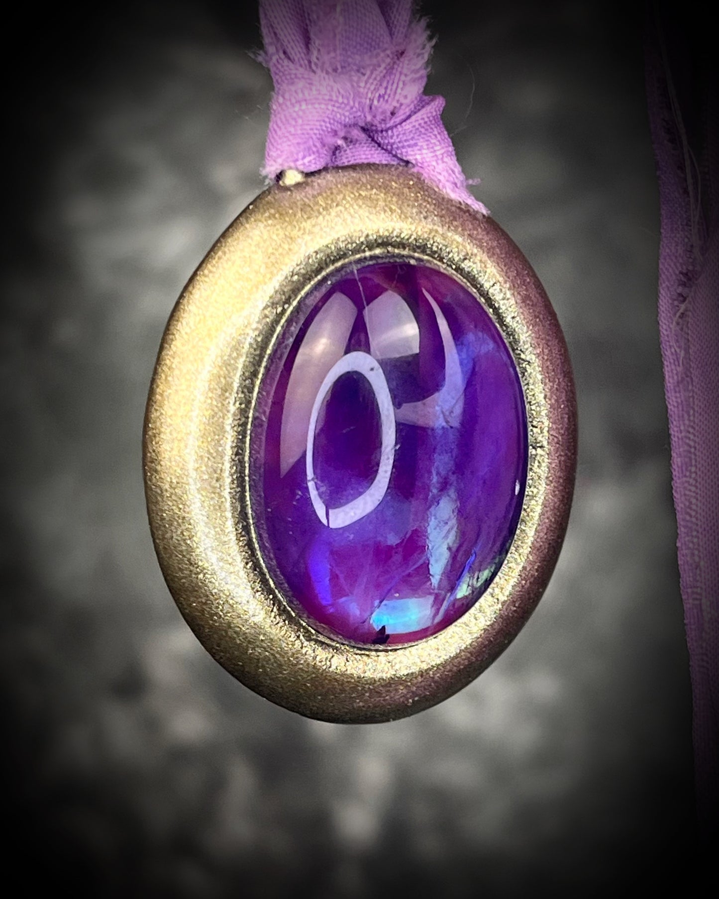 Mystical amethyst talisman with soft nebula glow, sculpted gold finish, and lilac recycled silk ties by Become Spellbound.