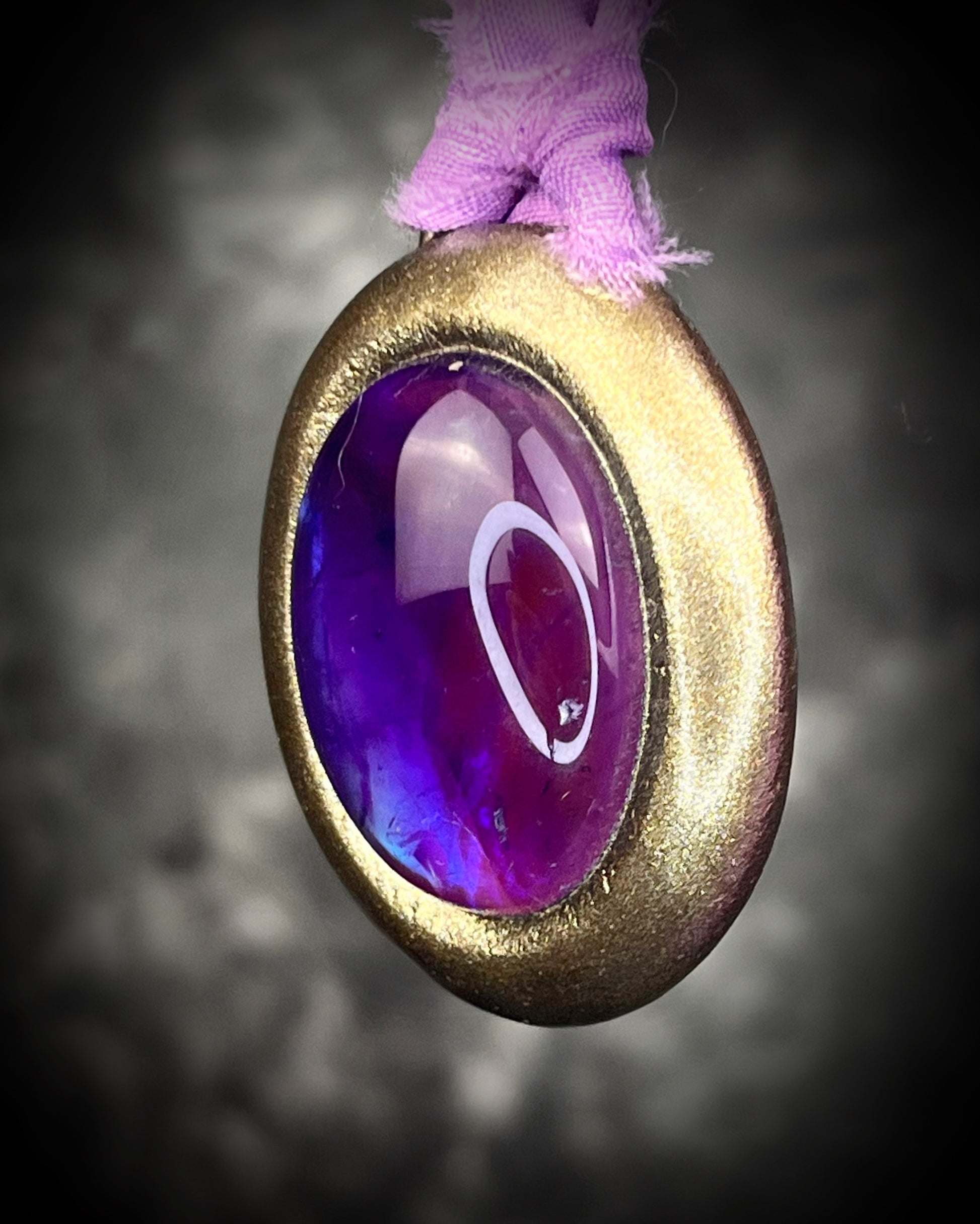 Mystical amethyst talisman with soft nebula glow, sculpted gold finish, and lilac recycled silk ties by Become Spellbound.