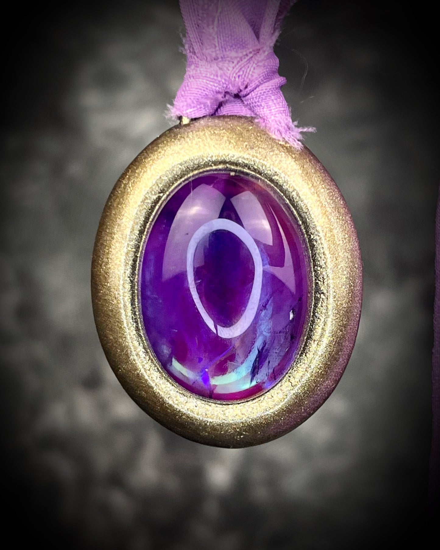 Mystical amethyst talisman with soft nebula glow, sculpted gold finish, and lilac recycled silk ties by Become Spellbound.